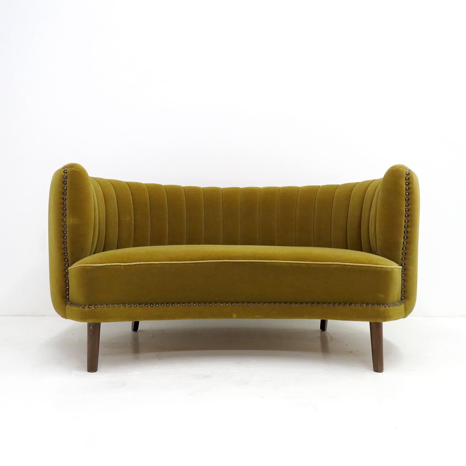 Wonderful curved Swedish modern settee, 1940s, in original chartreuse velvet with dark stained beech legs and nailed trims, some wear, staining and fading to the fabric.