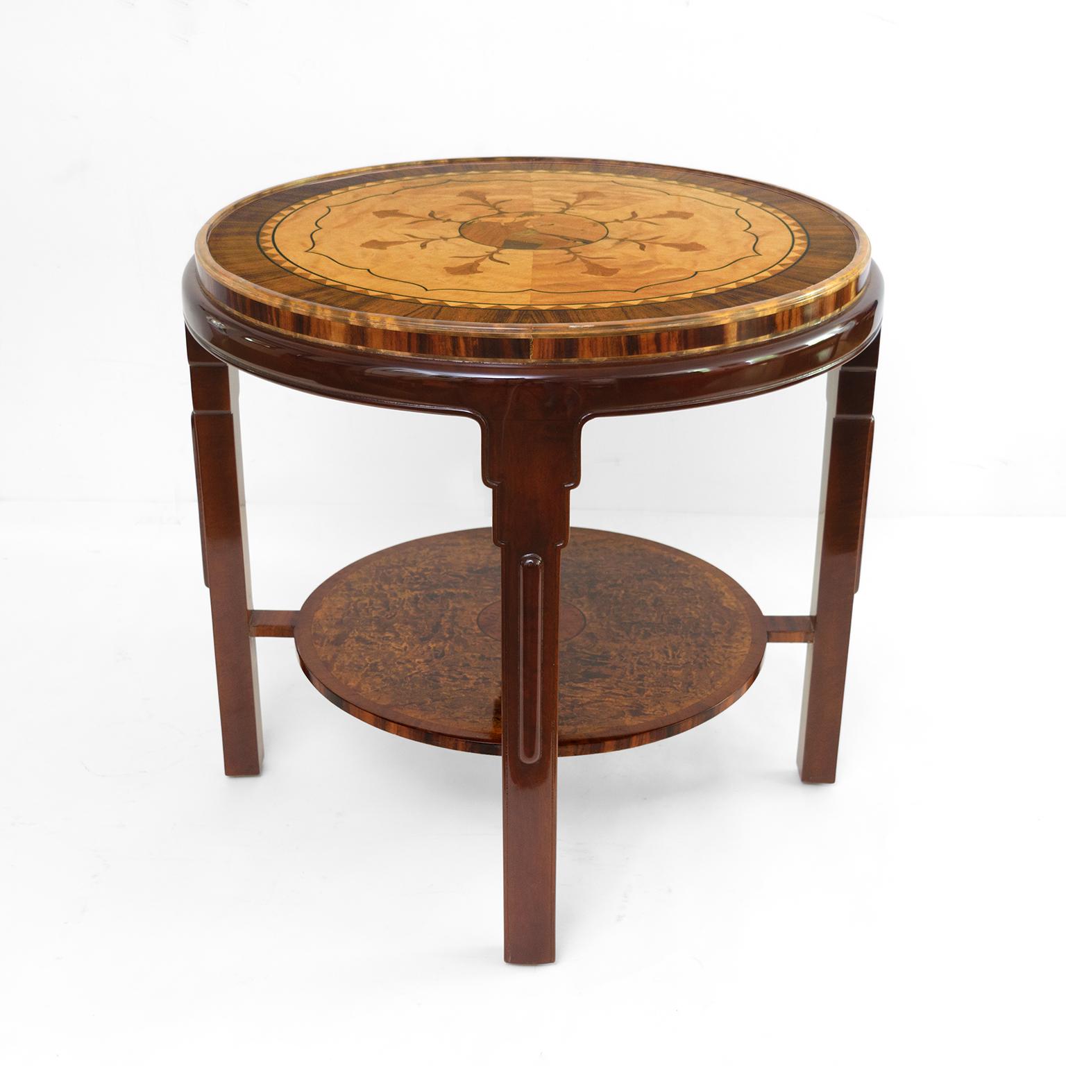 Swedish Grace (1920-35) side table lavishly decorated in a variety of exotic wood veneers. The top has a rosewood border which frames a circle of birch in eight sections, each displaying a stylized stem and flower. At the very center is a scene of