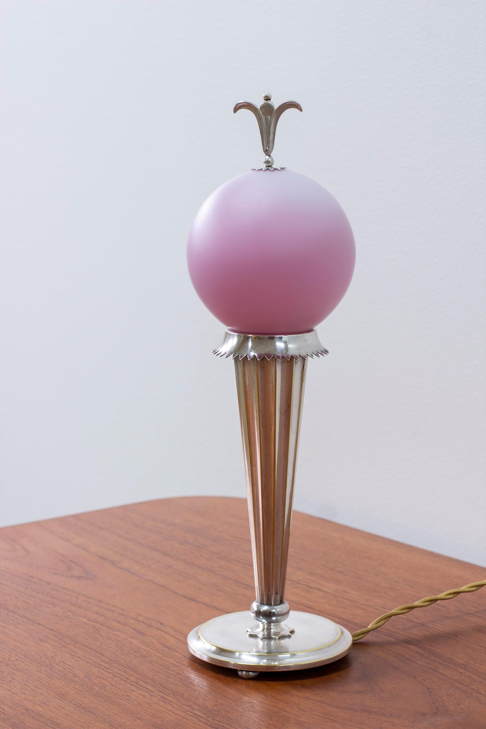 Table lamp 6853 designed by Harald Elof Notini. Produced by Böhlmarks lampfabrik in Stockholm Sweden ca 1924-35. Made from silver plated brass with pink Triplex glass shade with silver plated top decoration. Very good vintage condition with light