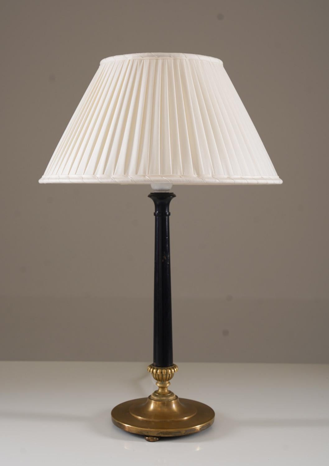 Esta elegante lámpara de sobremesa encarna la refinada estética del movimiento Grace sueco, elaborado por la estimada Nordiska Kompaniet durante la década de 1920. Su sofisticado diseño presenta un elegante tallo lacado en negro, elegantemente