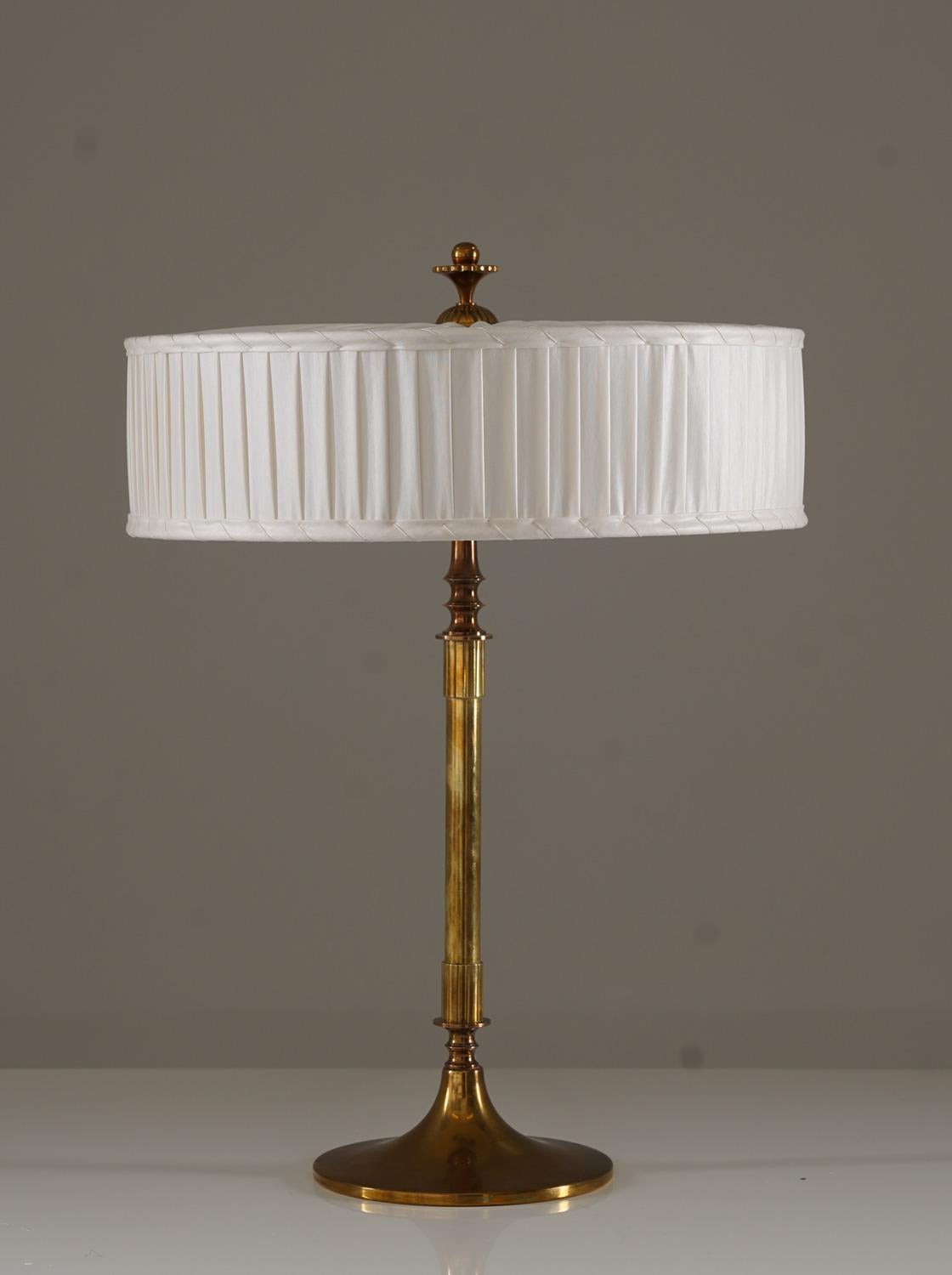 Cette lampe de table sophistiquée, modèle 6962A, a été produite par Böhlmarks à la fin des années 1920 et illustre le style Swedish Grace, une interprétation nordique raffinée du design du début du XXe siècle. Fabriquée en laiton poli, la lampe