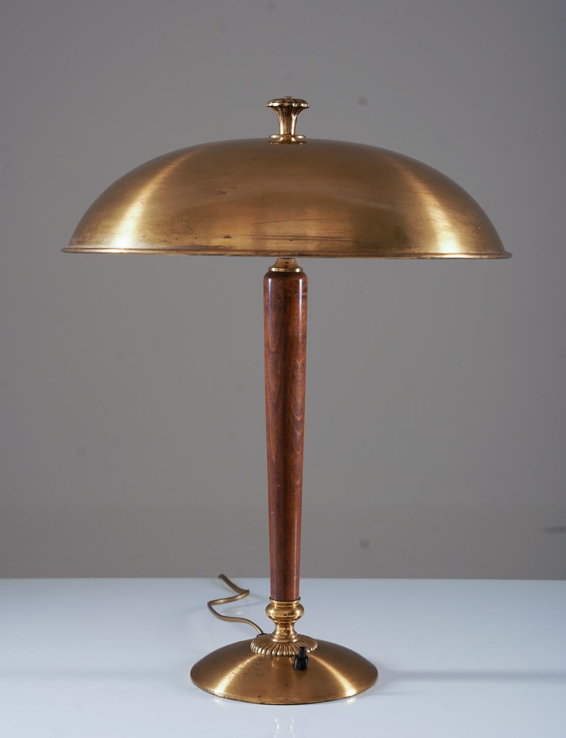 Elegant Scandinavian table lamp by Nordiska Kompaniet (NK), Sweden, 1920s.
This lamp is made of solid brass with details in mahogany.

Condition: Very good condition with patina and spots on the brass. The inner side of the shade has been