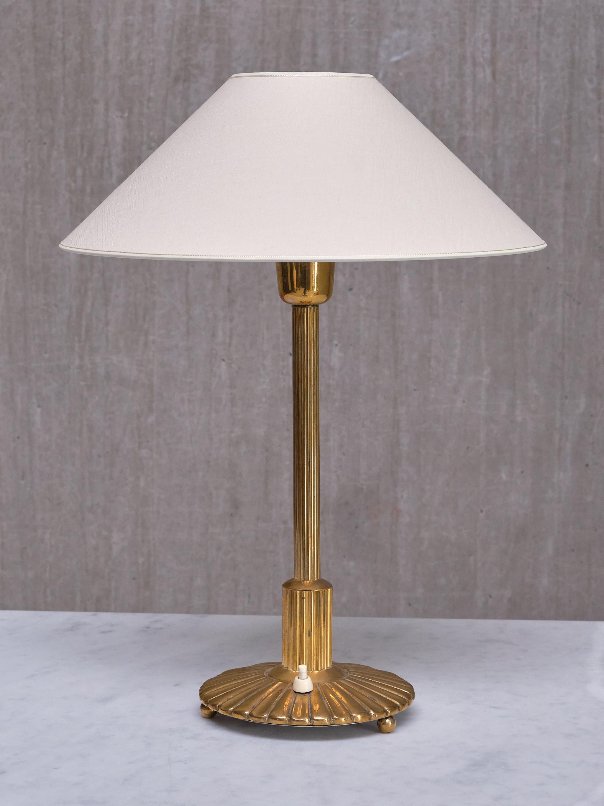 Cette élégante lampe de table a été conçue et produite en Suède à la fin des années 1930.
Le design décoratif est entièrement fabriqué en laiton massif, qui a développé une belle patine uniforme au fil du temps. La colonne centrale présente un