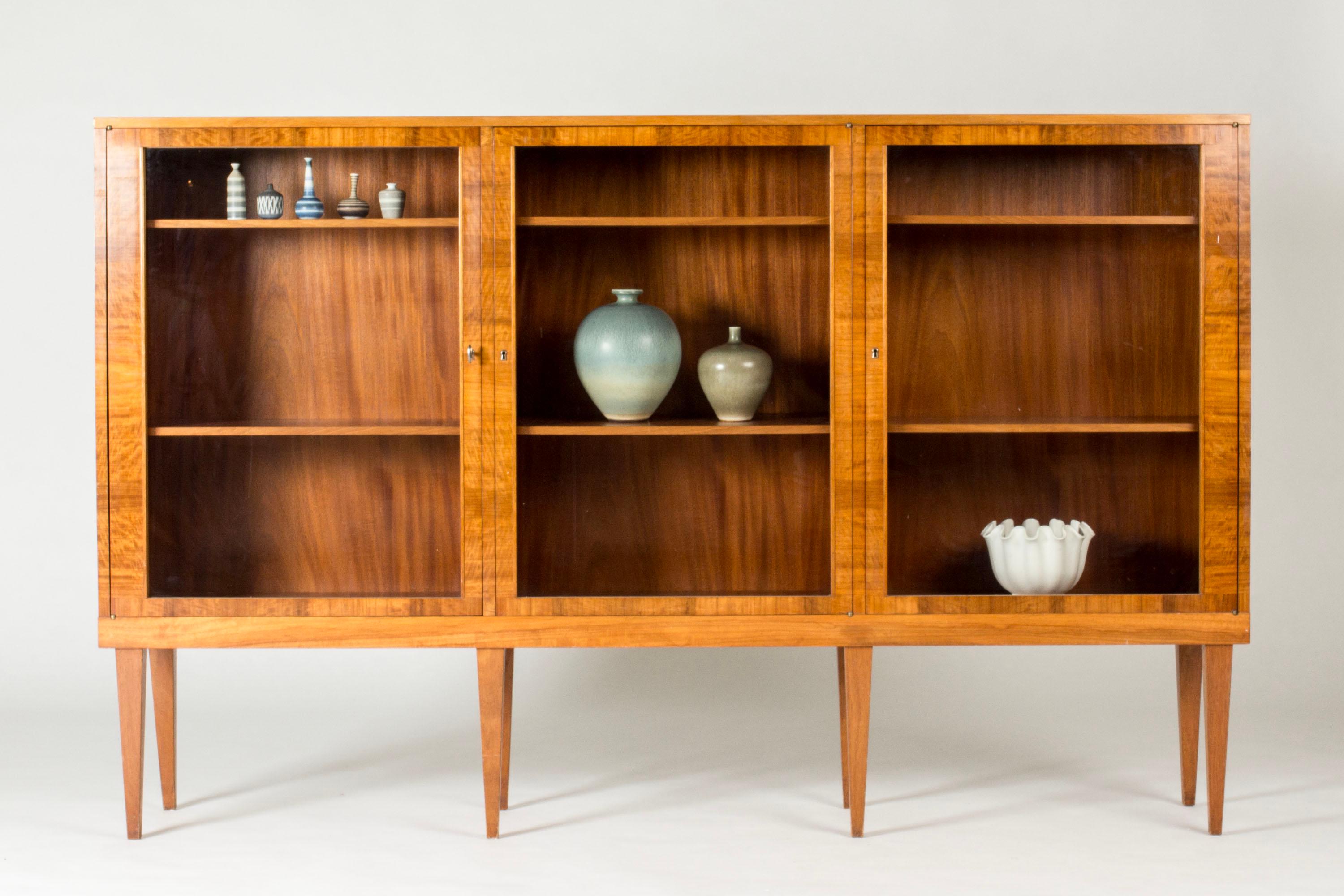 Elegant bookcase with vitrine doors by Carl Malmsten, perfect for organizing favorite books and objects. Made from mahogany with woodgrain laid in contrasting directions.
