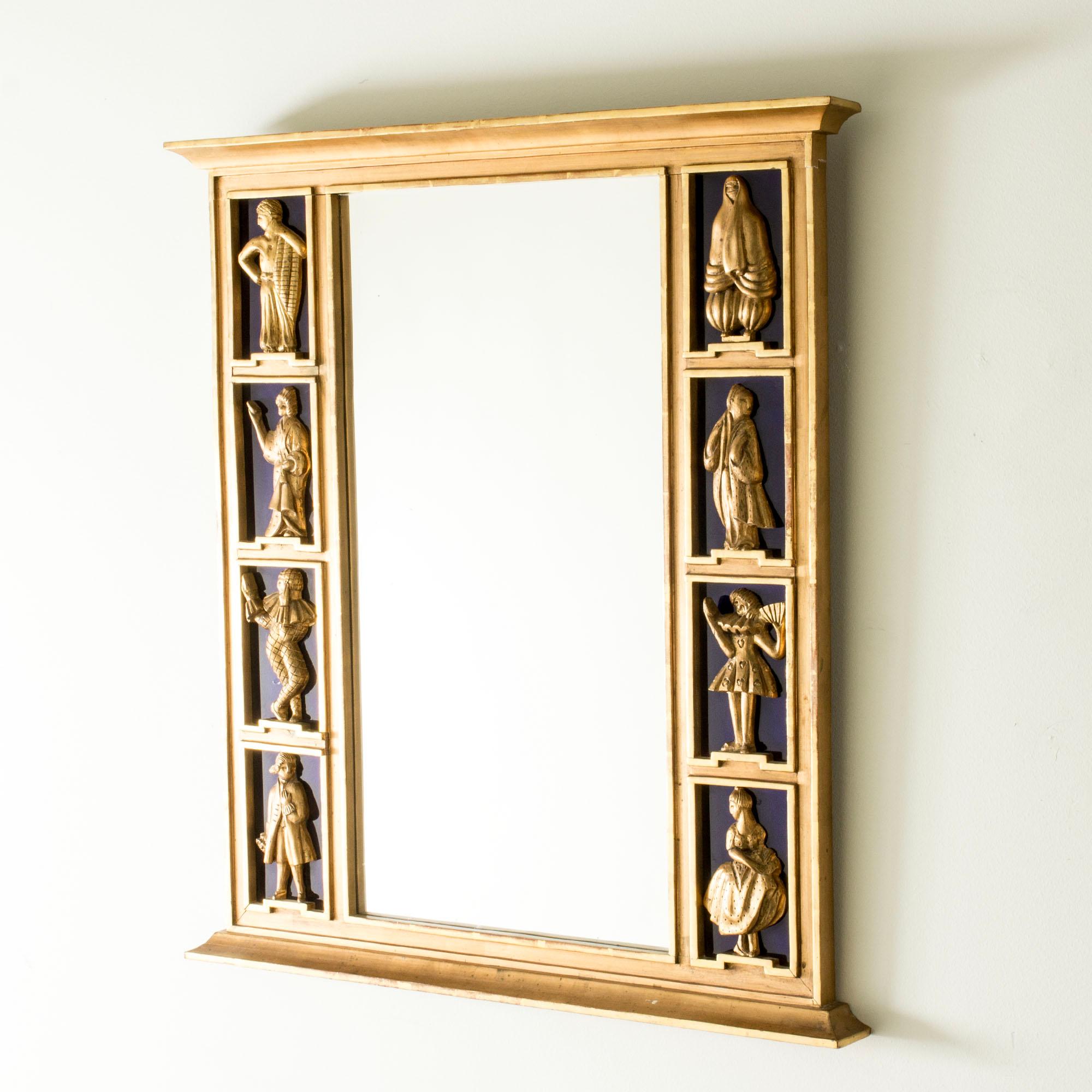 Impresionante espejo de pared Grace sueco, fabricado en madera con un elaborado diseño que representa a personas con trajes tradicionales de distintas partes del mundo. Expresión teatral. Dorado con cristal azul oscuro detrás de las figuras.