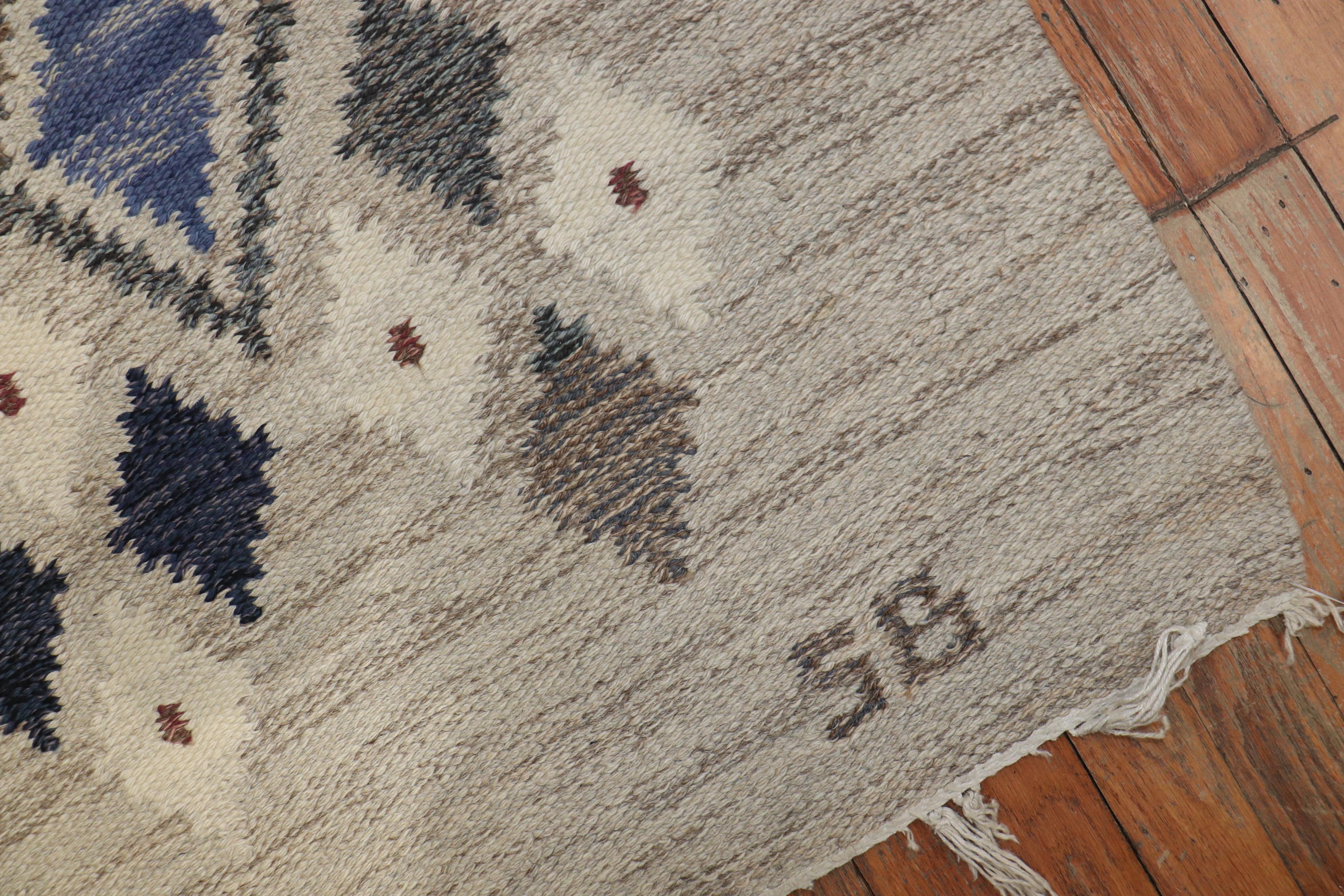 A Swedish flat weave rug with a diamond motif in gray ivory and blue designed by Sigvard Bernadotte. Signed SB Lower Right Corner, circa 1950 

Measures: 7'6'' x 8'4''

Sigvard Bernadotte is best known for his work designing silver for the