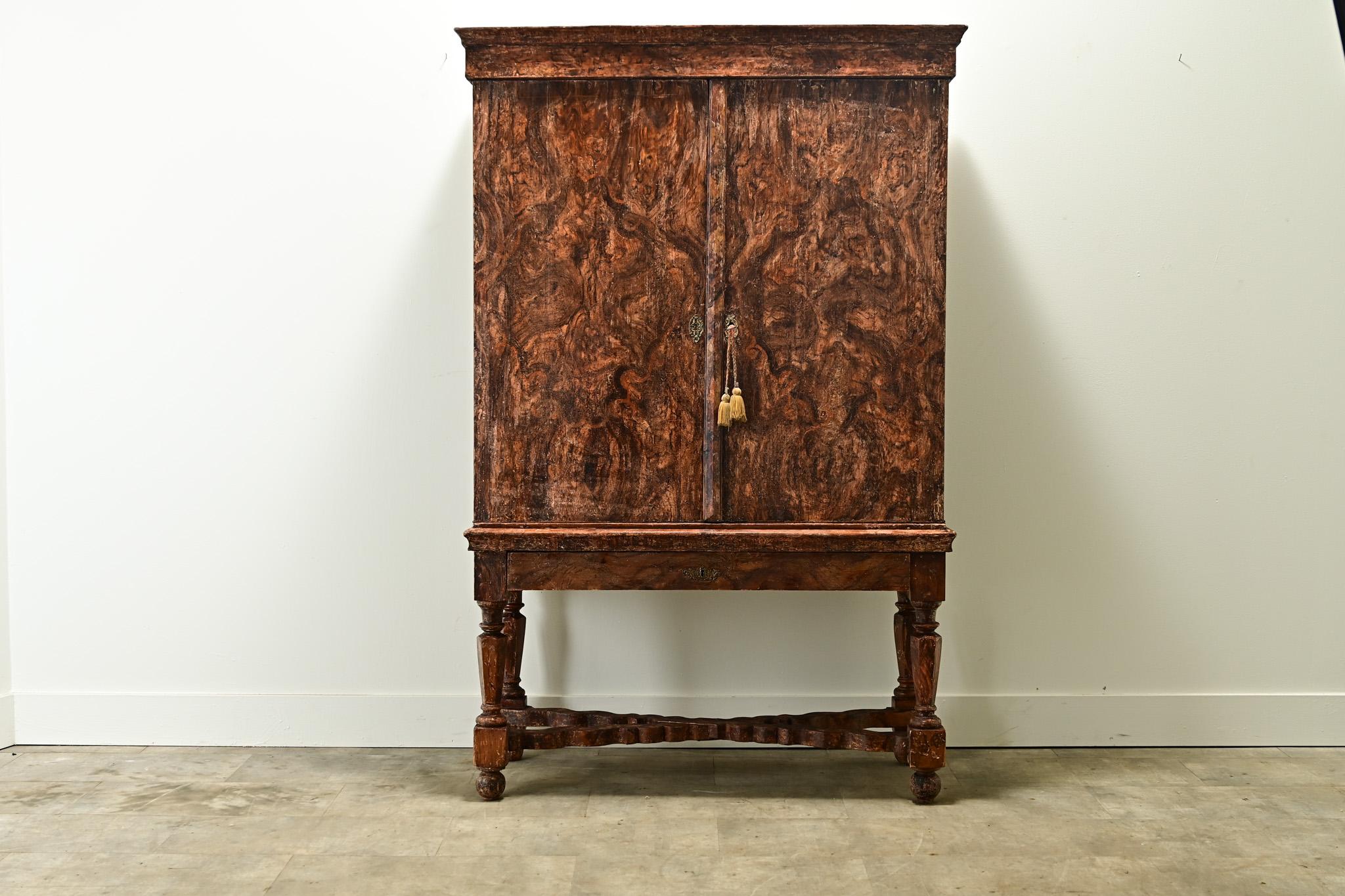 This Swedish Gustavian faux bois cabinet was made in the 1600’s and makes a statement. This sturdy solid pine cabinet has a faux bois paint finish that has been hand-scraped back to its original finish. The pair of cabinet doors open with a working