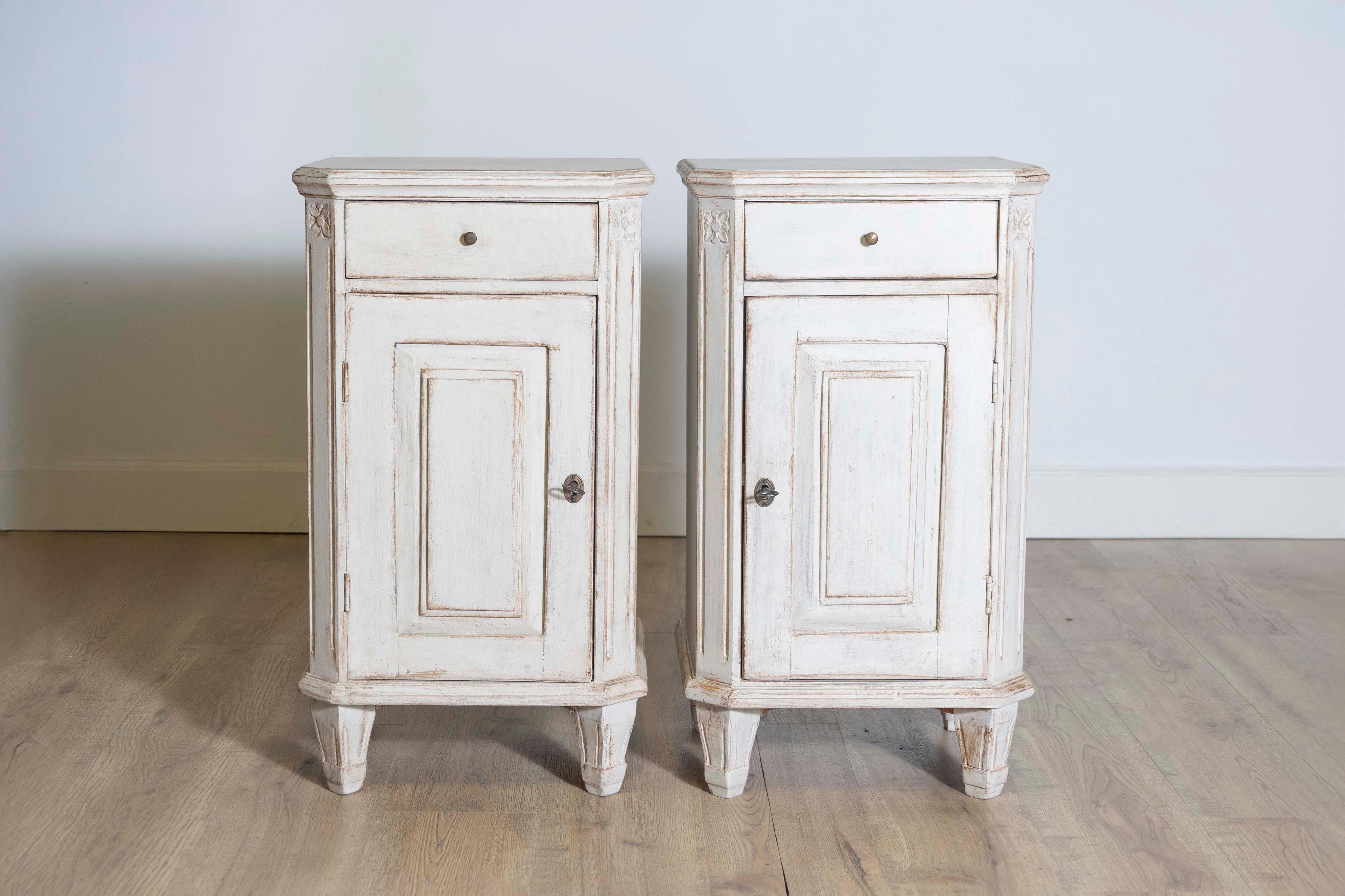A pair of Swedish Gustavian style bedside tables from circa 1880 with light gray finish, single drawer over single door, canted side posts and tapered feet. This pair of Swedish Gustavian style bedside tables from circa 1880 exudes the serene