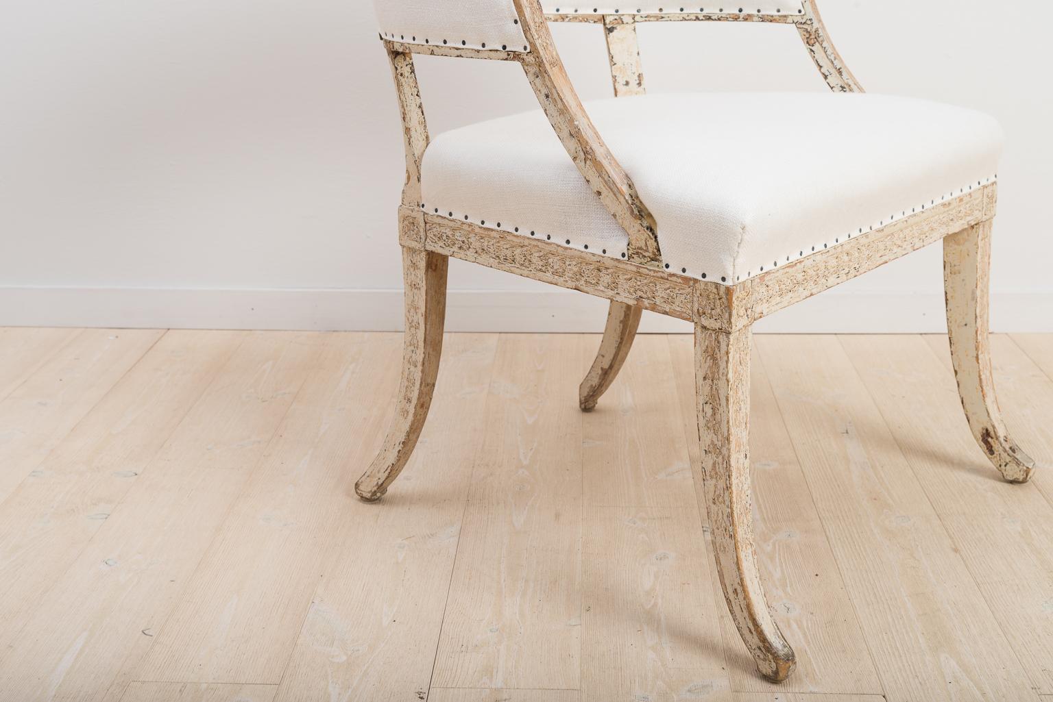 Swedish Gustavian barrel back armchair with carved wooden decorations. Dry scraped to original paint. Renovated padding and new upholstery in linen made according to traditional techniques. Older enforcements on the underside in the form of corner