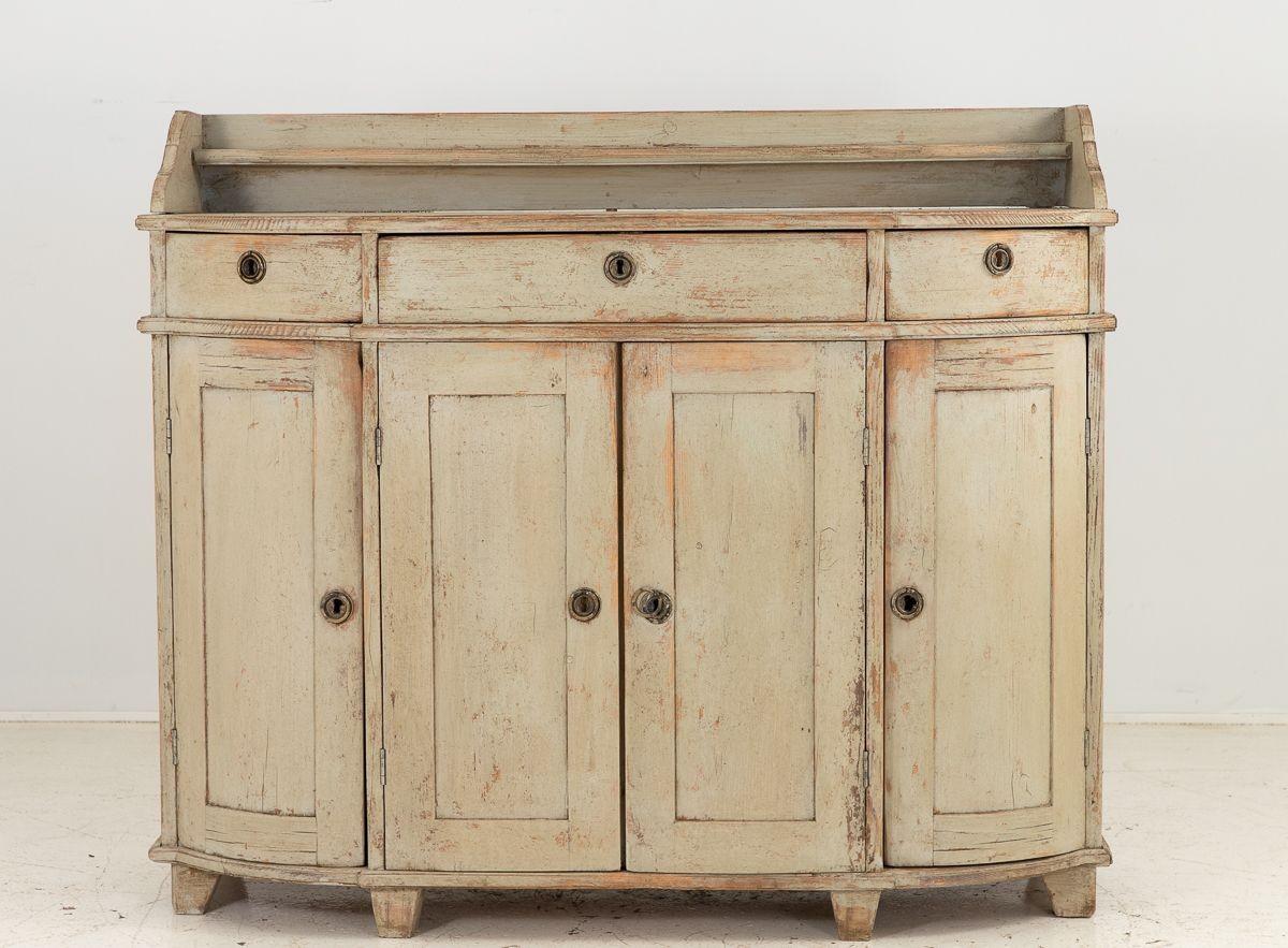 The Swedish Gustavian 19th-century Buffet is a stunning piece of furniture that epitomizes the grace and elegance of Swedish design. Painted in a soft Swedish gray color, it exudes a serene and sophisticated aura. The buffet features four doors that