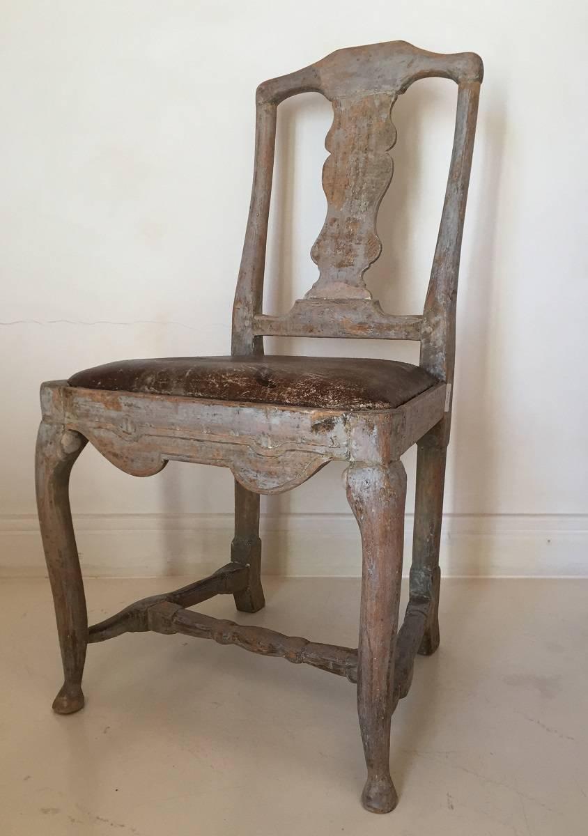 Good 18th century Swedish Gustavian chair with original leather seat and faded grey paint. The seatfilling and springs have been renewed with conservation of the original leather. Its fluent lines are beautifully crafted out of beechwood and