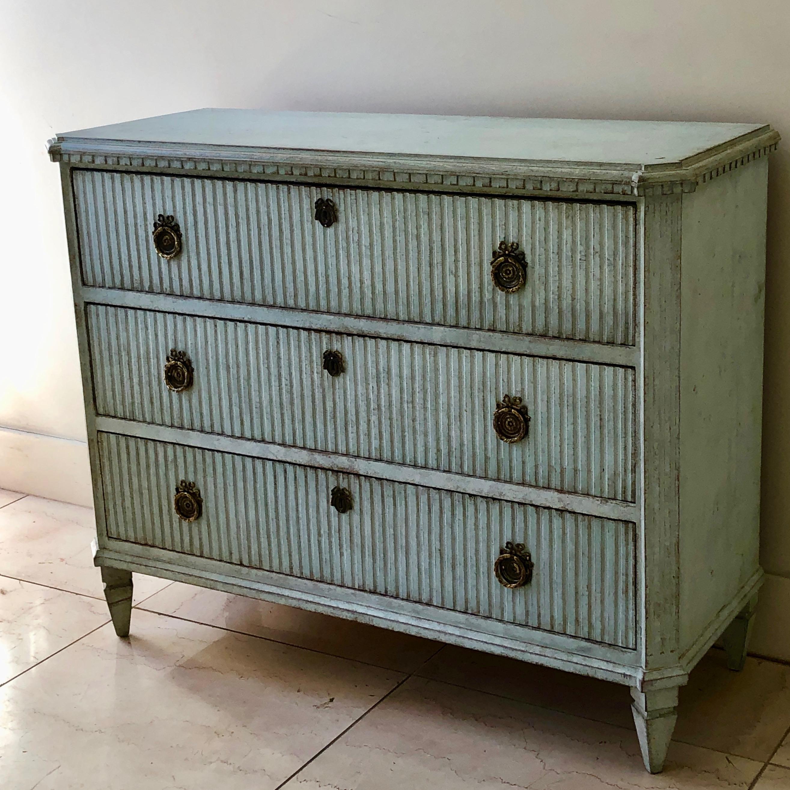 Early 19th century period Swedish Gustavian chest of drawers with Classic reeded drawer fronts with handsome hardwares and dentil molding in palest blue color under the shaped top, Sweden, circa 1820. 
Surprising pieces and objects, authentic,