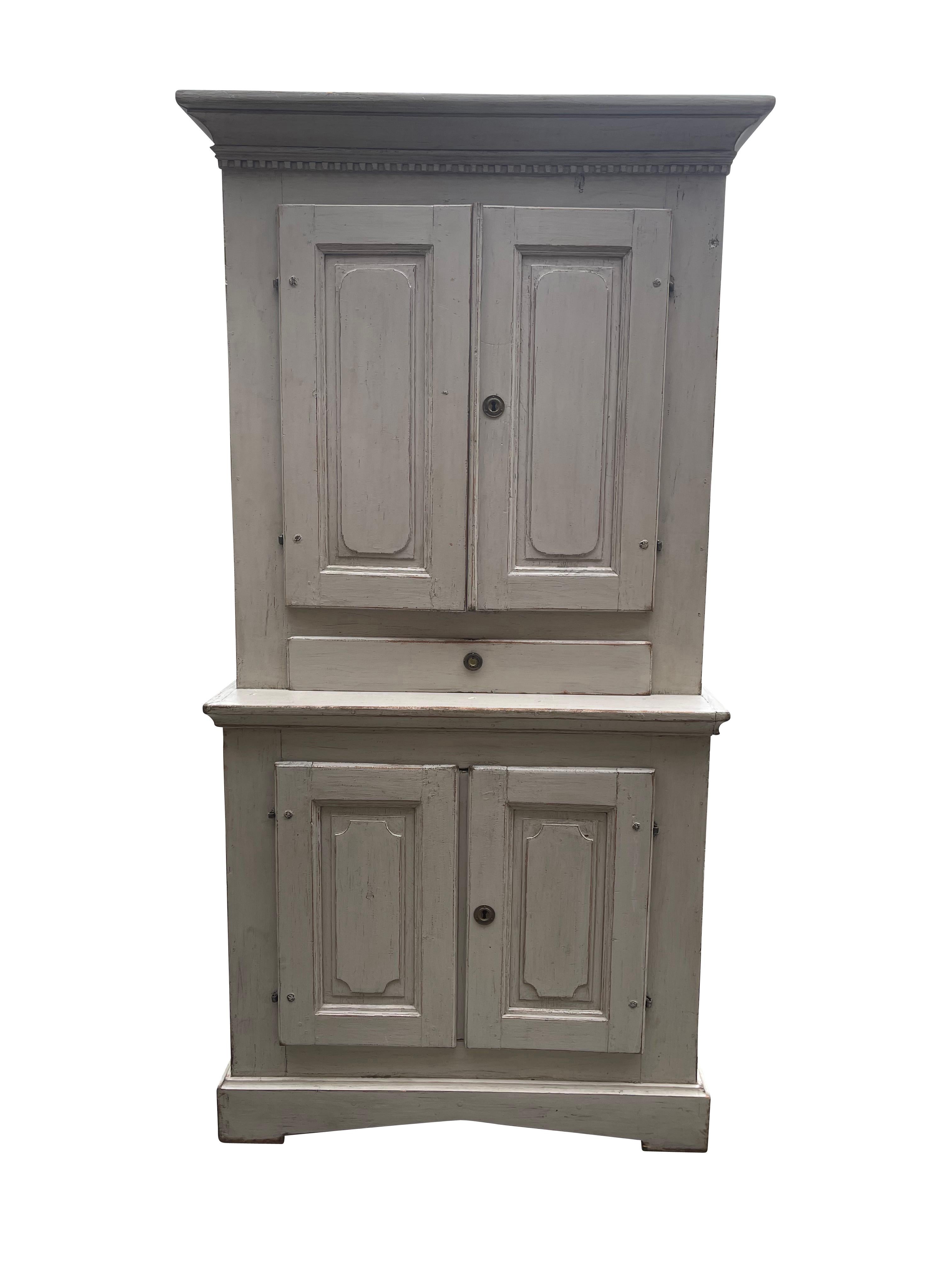 Perfect and already set up a media cabinet, this Swedish Gustavian cupboard in a lime-washed finish, 19th century, has two doors over a single drawer over two cupboard doors on a bracket base, with neoclassical dental molding detail, the interior of