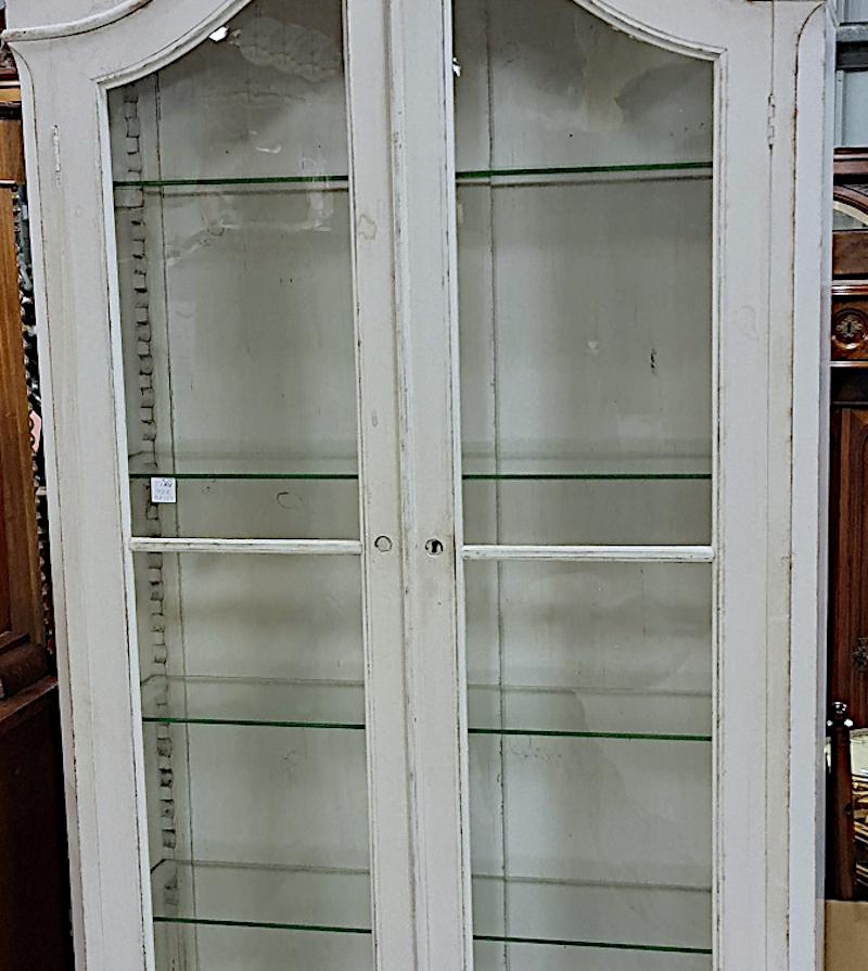 Beautiful Swedish antique Gustavian vitrine display cabinet linen press armoire in later white paint with glazed doors and glass shelving, curved feet and remarkable carved top, circa 1850-1880.

4 shelves inside the cabinet and a lower drawer for