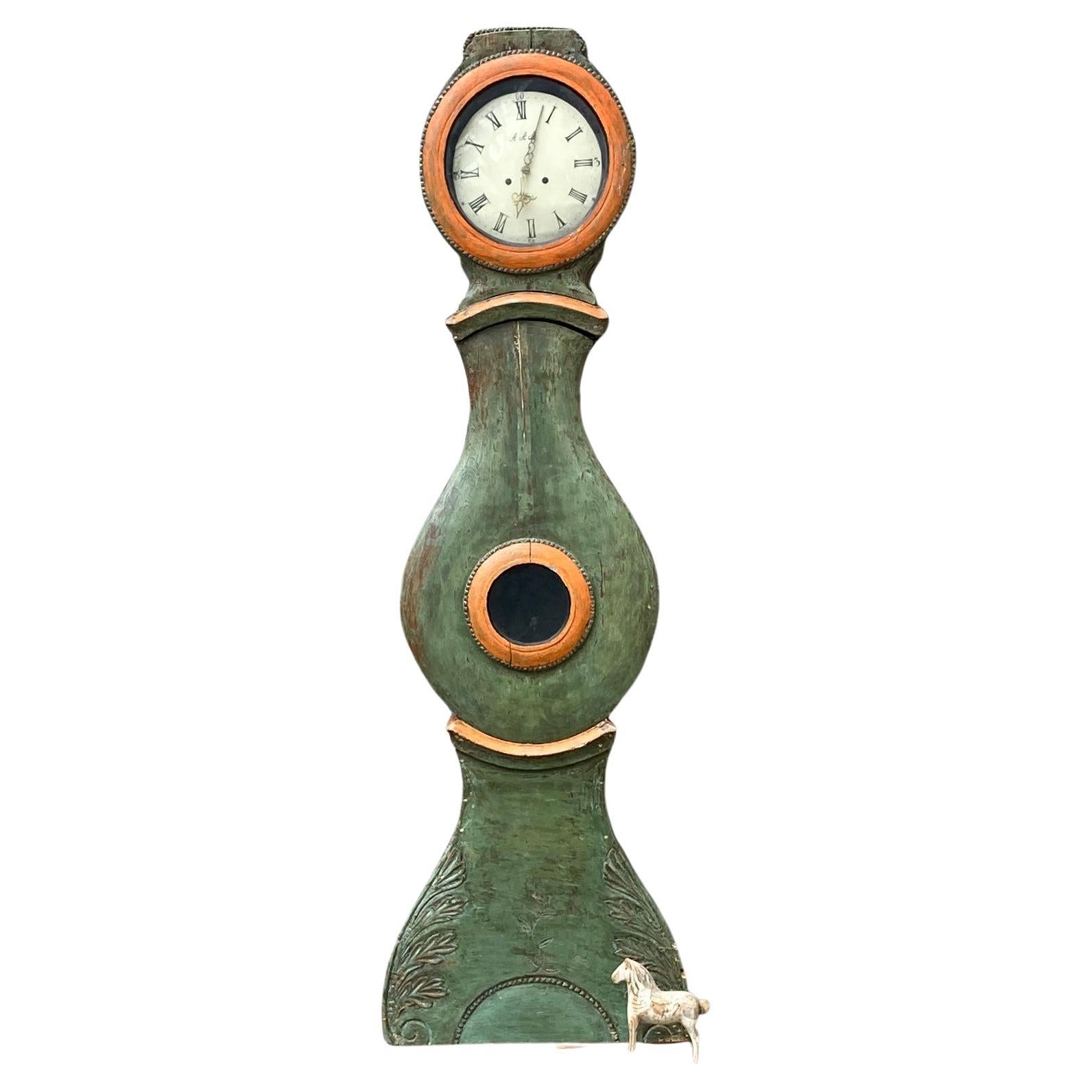 Schwedische antike Mora antiques Uhr aus den frühen 1800er Jahren mit grüner Farbe mit orangefarbenen Details, die auf das Gehäuse gemalt sind. 
Das Uhrwerk wird so verkauft, wie es ist, und sollte nur als dekoratives Stück betrachtet werden, auch