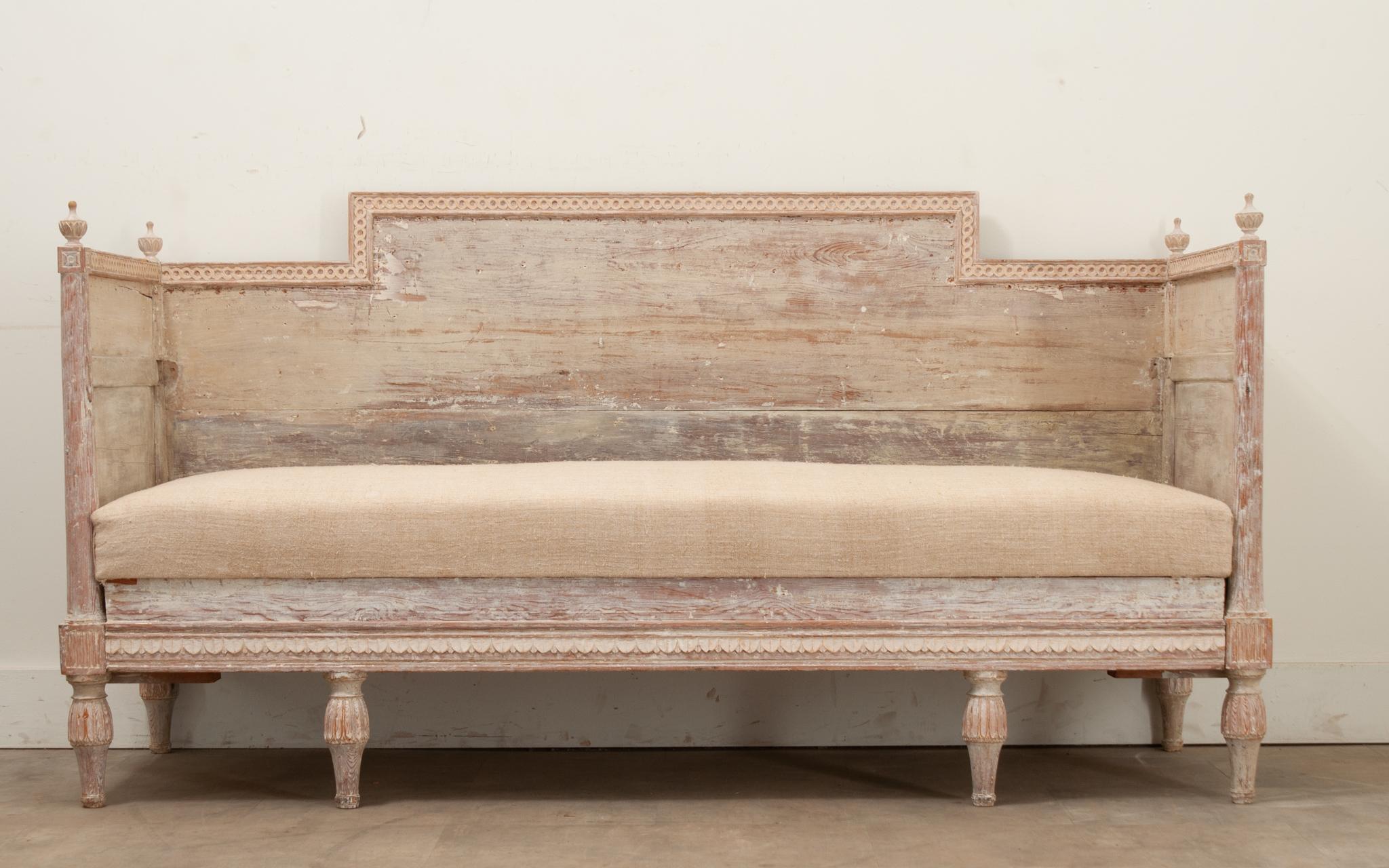 A Swedish 18th Century Period Gustavian banquette with its original hand-scraped painted finish. The solid constructed frame makes a statement and has a removable seat cushion. The legs of the banquette can slide out, converting this Swedish sofa