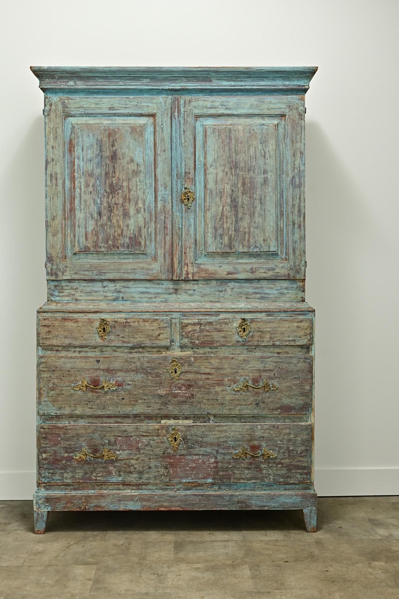 A Gustavian style painted cabinet made in Sweden circa 1860. This buffet over chest has its original dry scraped painted finish on its exterior. The top cabinet doors open to reveal a rogue interior with three fixed shelves at 13”D. The top shelf is