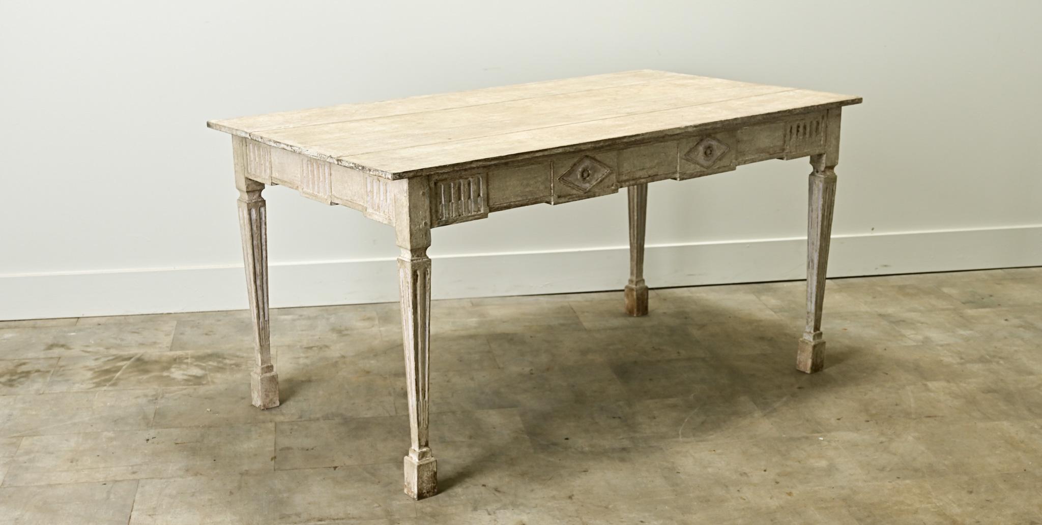 A large Swedish Gustavisn style center table with its original paint finish. This table can be used as a desk, console or center table as it is finished on all sides. The simple top sits over a carved table apron with classic diamond shapes and