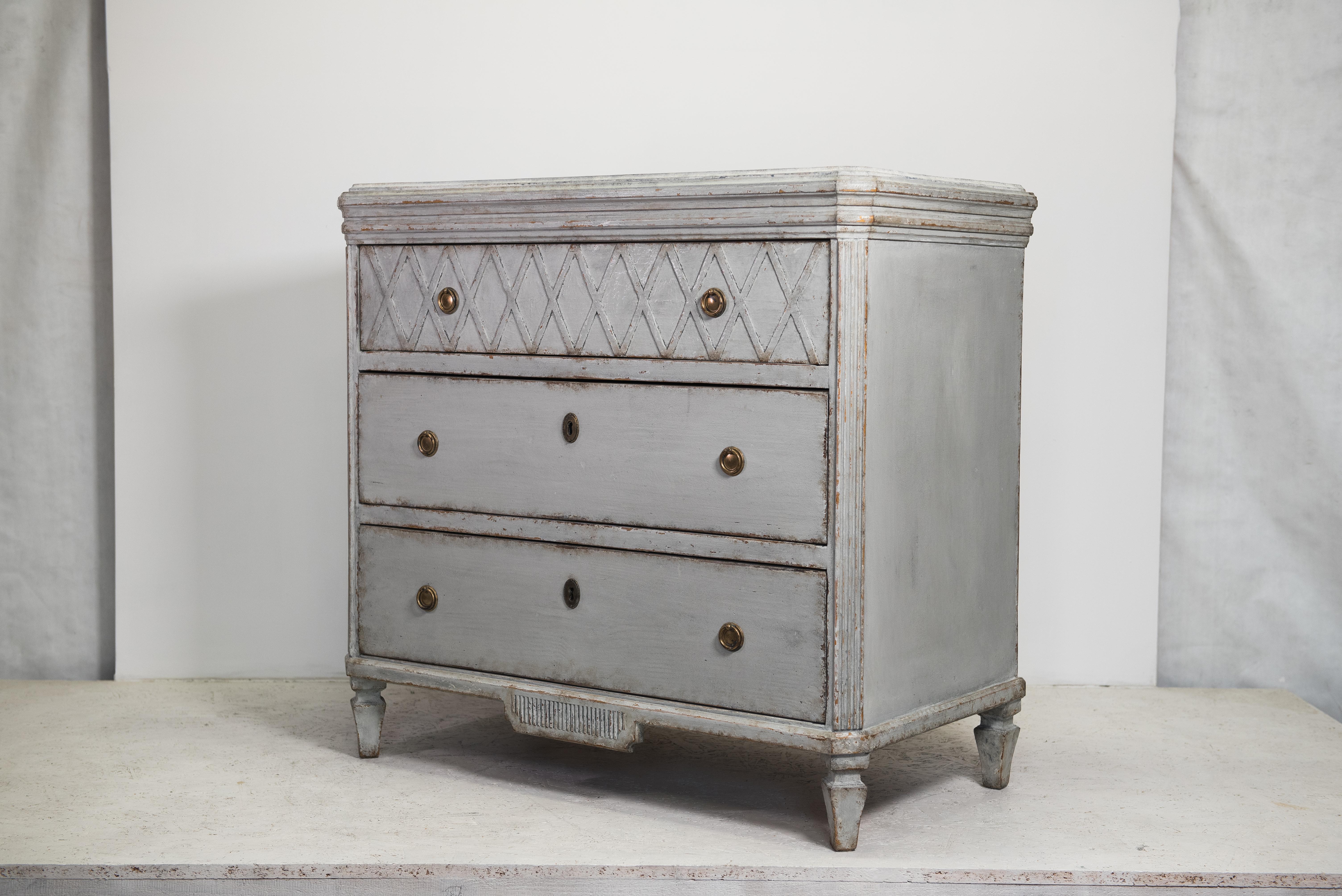 C 1845 antique Swedish Gustavian painted chest of 3 drawers commode with detailed decorative motifs on the top rail, front and brass detailing.

It has 3 drawers with brass ring pulls and a carved plinth and feet with column detail on the front