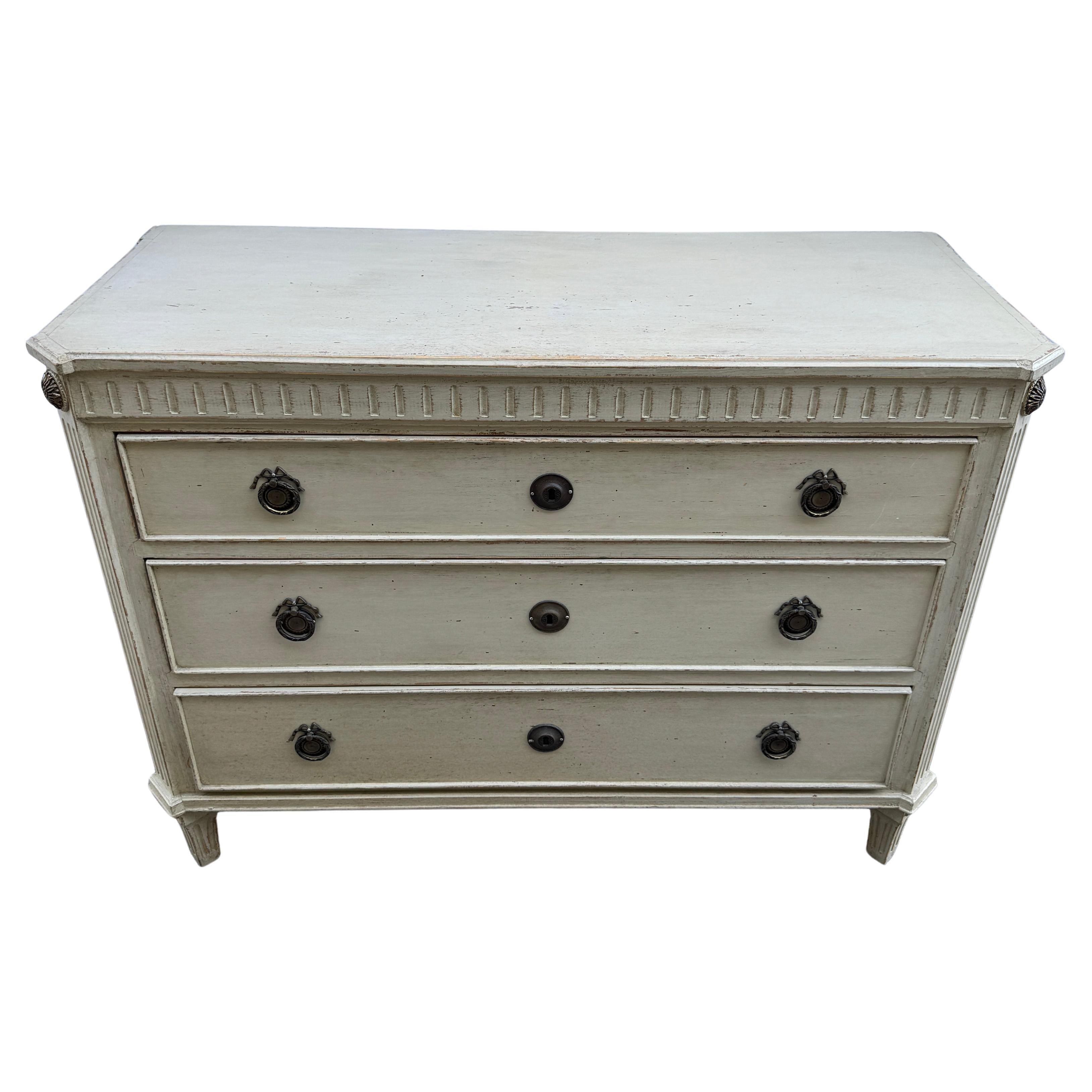 Painted Chest of Drawers or Commode with Fluted Carvings 

Swedish Gustavian chest with Louis XVI drawer pulls as well as brass corner pieces featuring classic style rosettes. This very sturdy piece is a very neutral color making it very versatile.