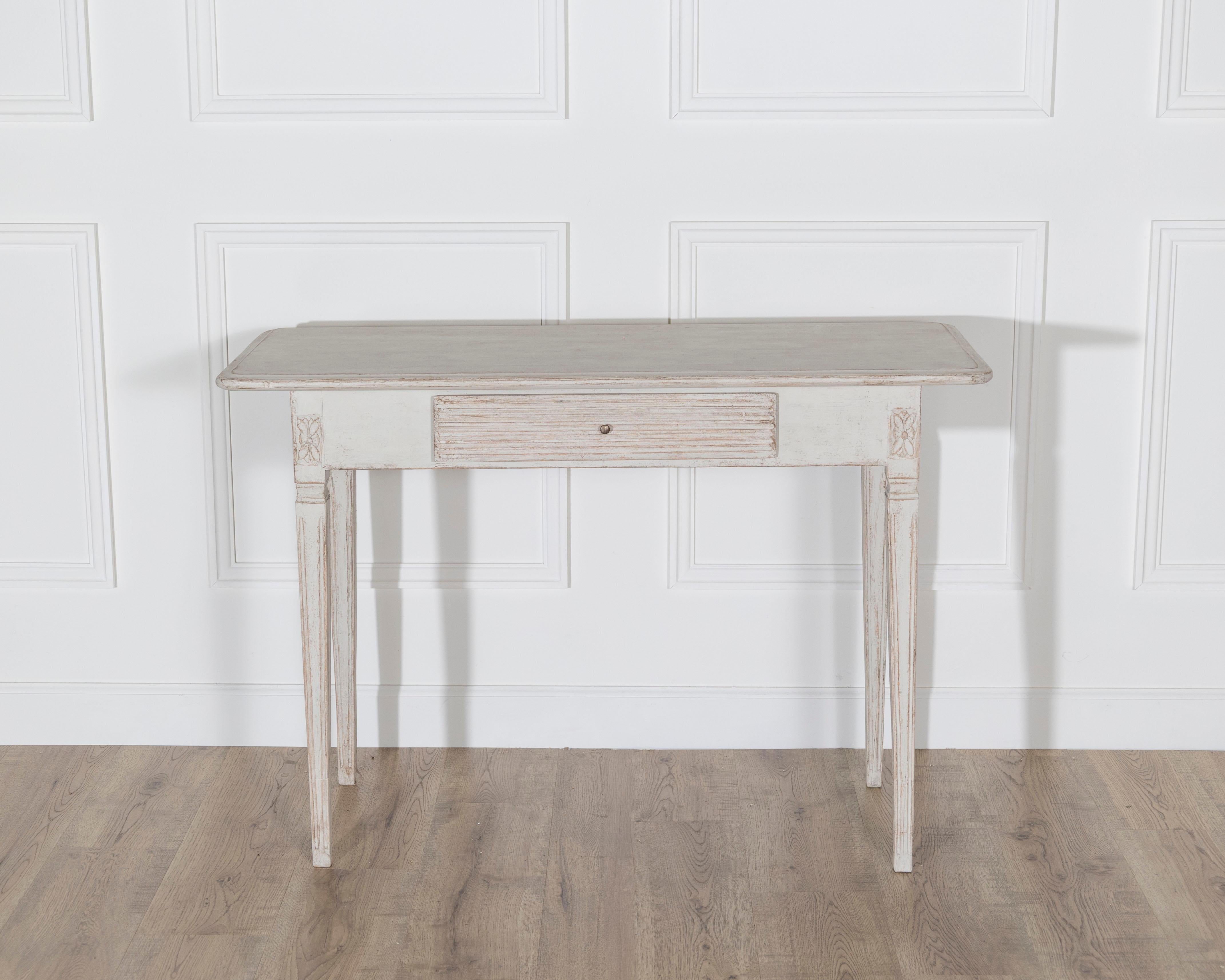 A Swedish Gustavian side table from the 19th century, combining graceful proportions with the understated elegance of Scandinavian design. Crafted in pine and retaining its original painted surface, now softly worn to a light patina, the table