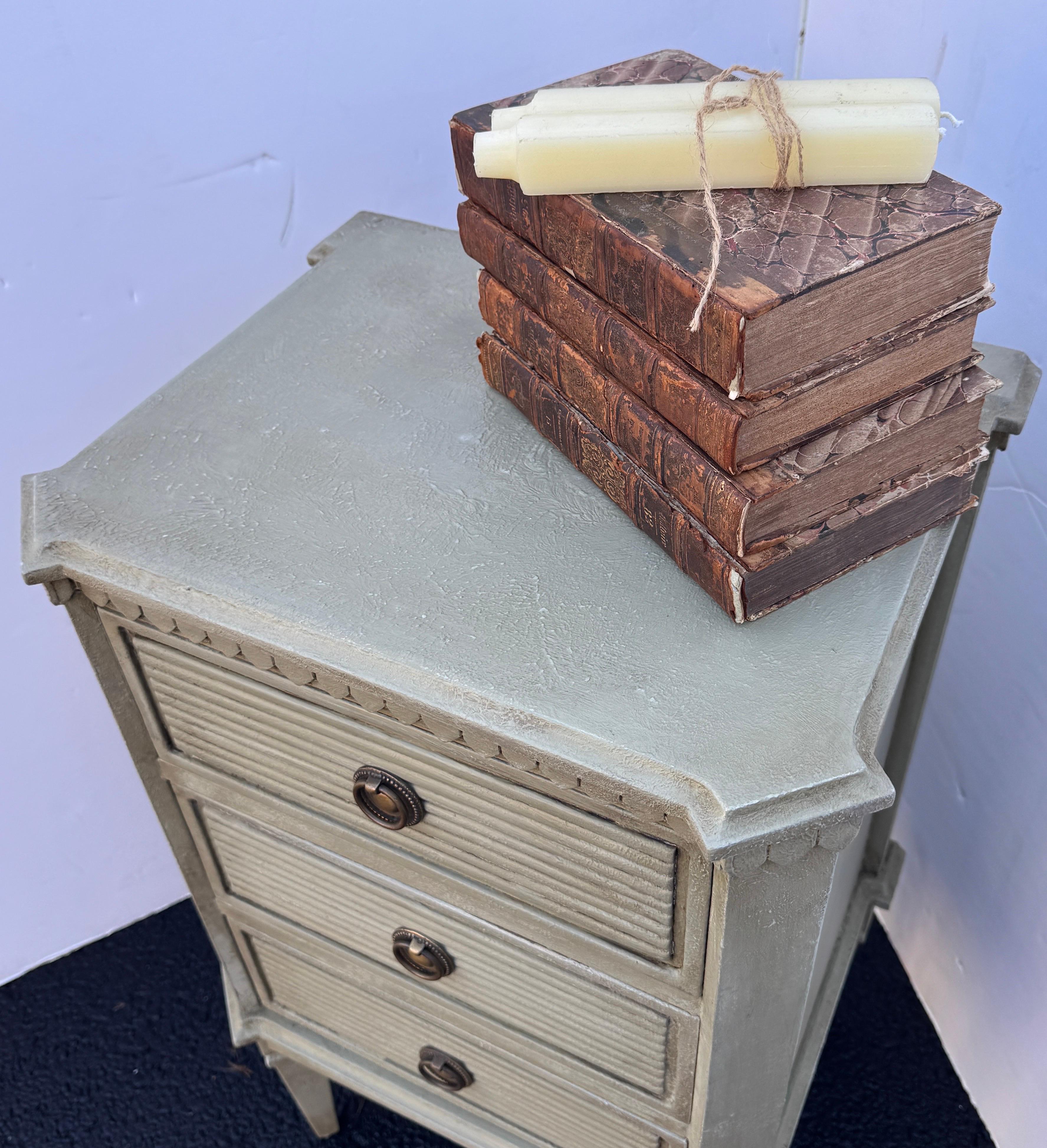 Pintada a mano, en un maravilloso color verde neutro escandinavo, cómoda o mesilla de noche de estilo Gustaviano. Esta pieza está fabricada en madera maciza con un acabado envejecido aplicado a mano y herrajes con anillas de latón. Estas cómodas