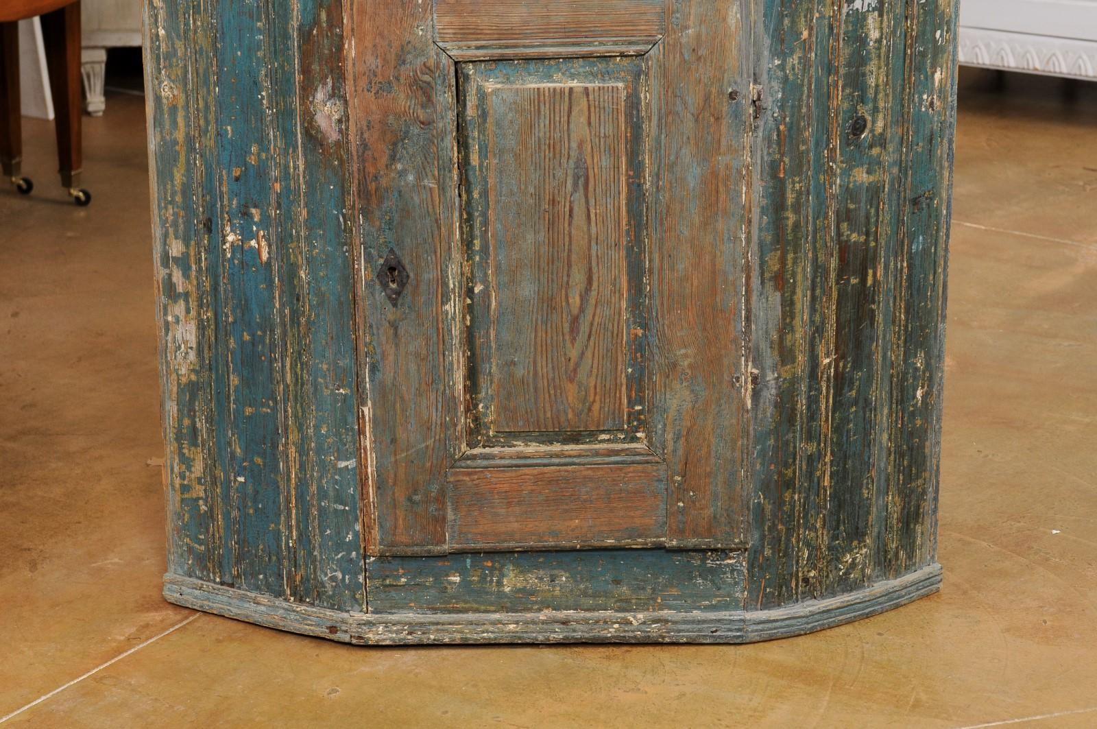 Meuble d'angle en bois peint d'époque gustavienne suédoise, datant de la fin du XVIIIe siècle, avec une peinture bleue, une seule porte et un aspect usé par le temps. Créée en Suède au cours de la dernière décennie du XVIIIe siècle, cette armoire