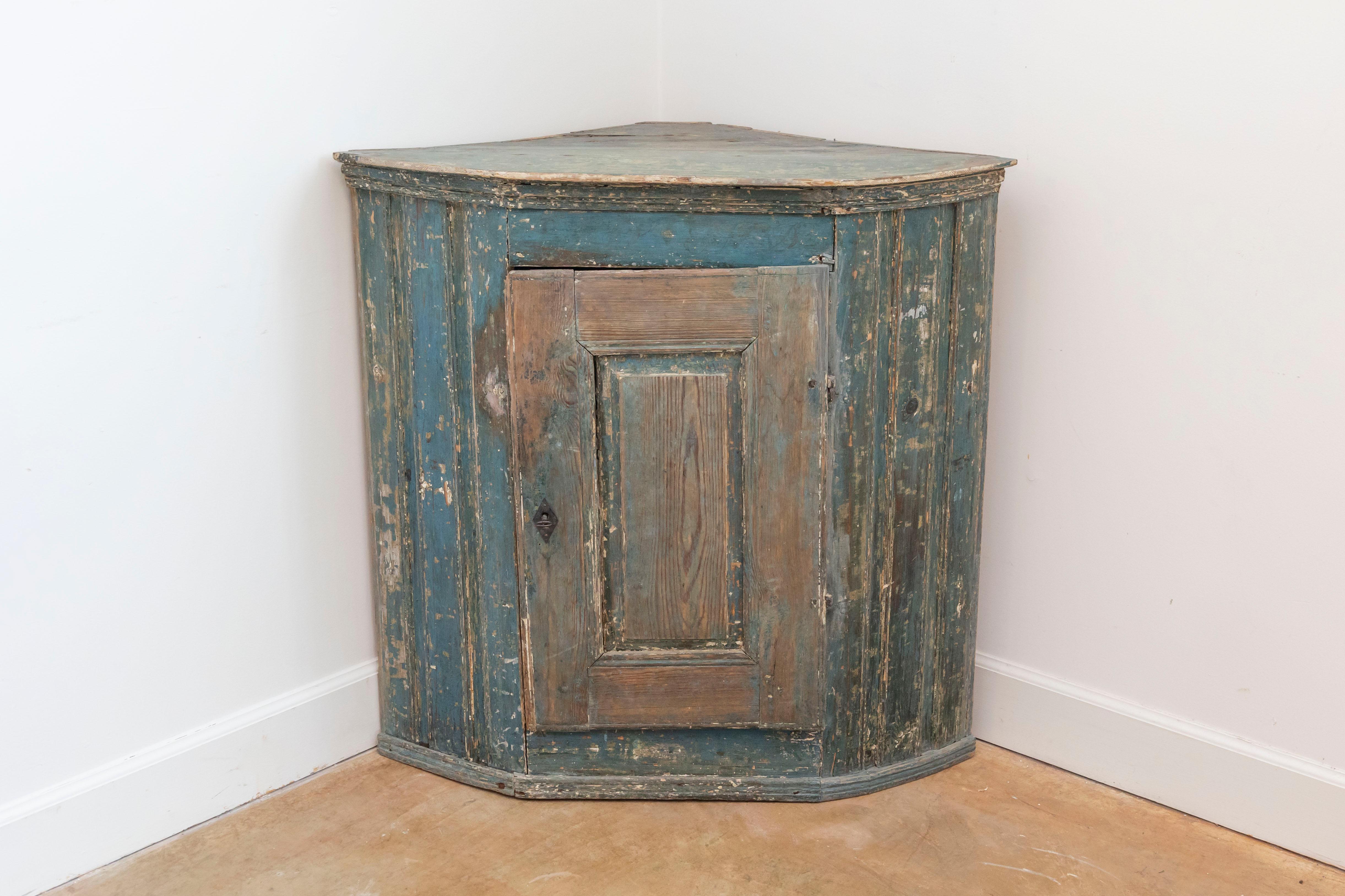 Armadio angolare a muro in legno dipinto di epoca gustaviana, risalente alla fine del XVIII secolo, con vernice blu, un'anta singola e un aspetto rovinato dalle intemperie. Creato in Svezia durante l'ultimo decennio del XVIII secolo, questo mobile