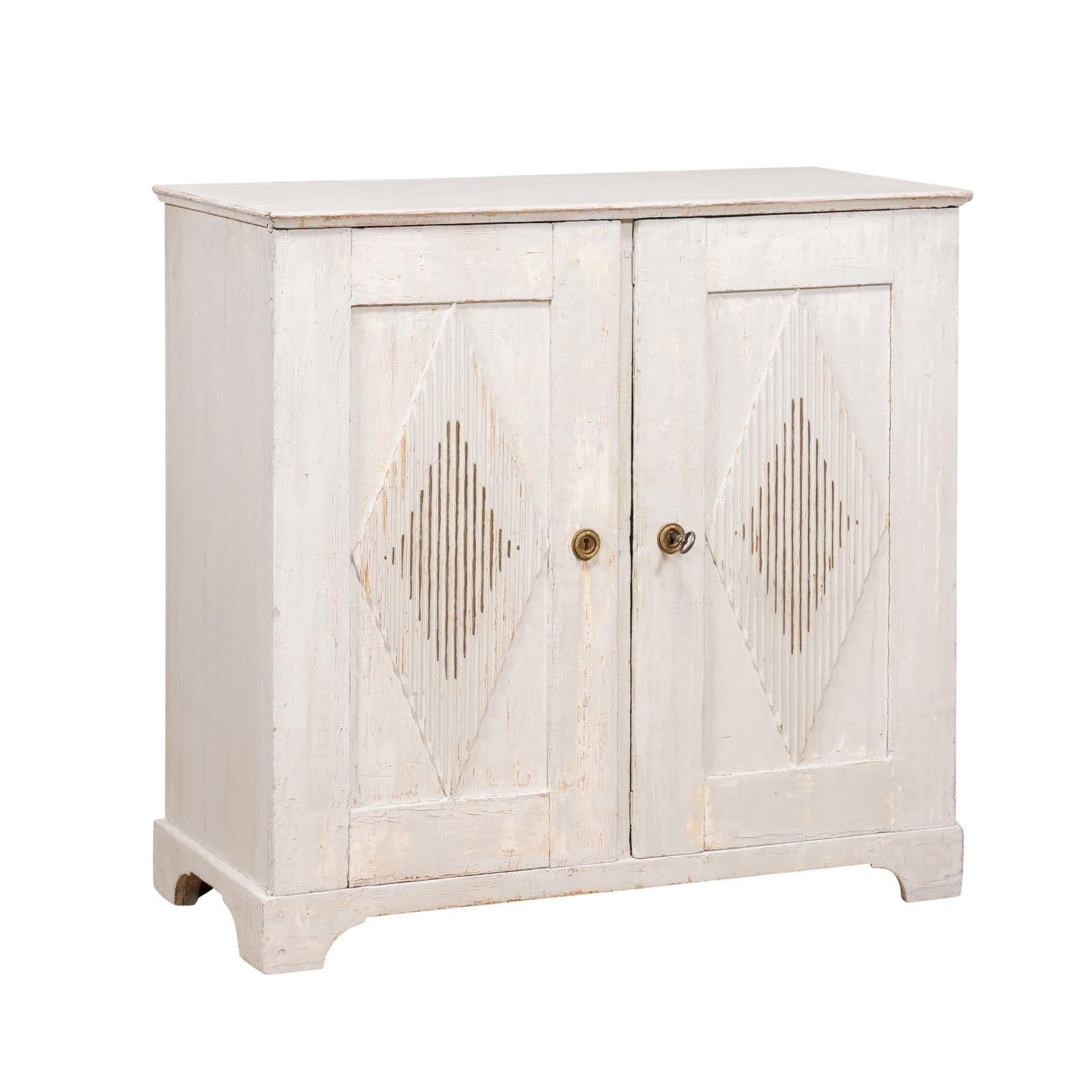A Swedish Gustavian period sideboard from circa 1810 with gray painted finish, carved diamond motifs, two doors and hidden drawers. This Swedish Gustavian period sideboard from around 1810 exudes timeless elegance. Its dove gray painted finish, with