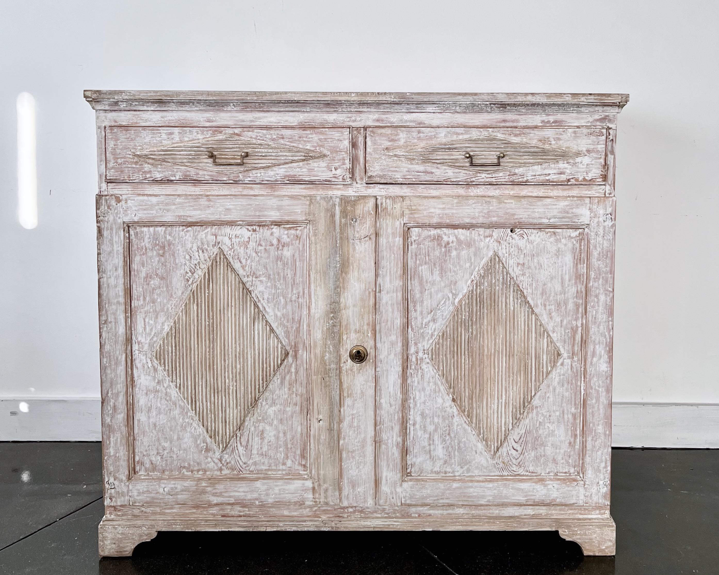 A richly, exclusively carved Swedish Gustavian period sideboard has reeded paneled doors and drawers with central diamond shape lozenges in hand scraped patina - in classic Gustavian manor. This antique sideboard offers plenty of practical storage