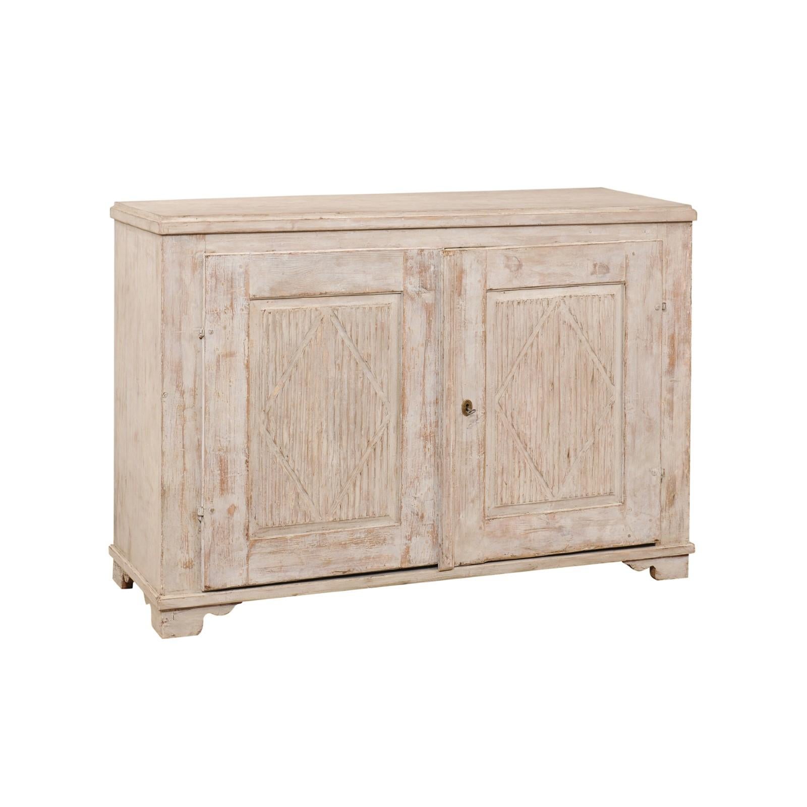 A Swedish Gustavian period painted wood sideboard from the early 19th century, with reeded doors, diamond motifs and carved ogee bracket feet. Created in Sweden during the first quarter of the 19th century, this Gustavian sideboard features a