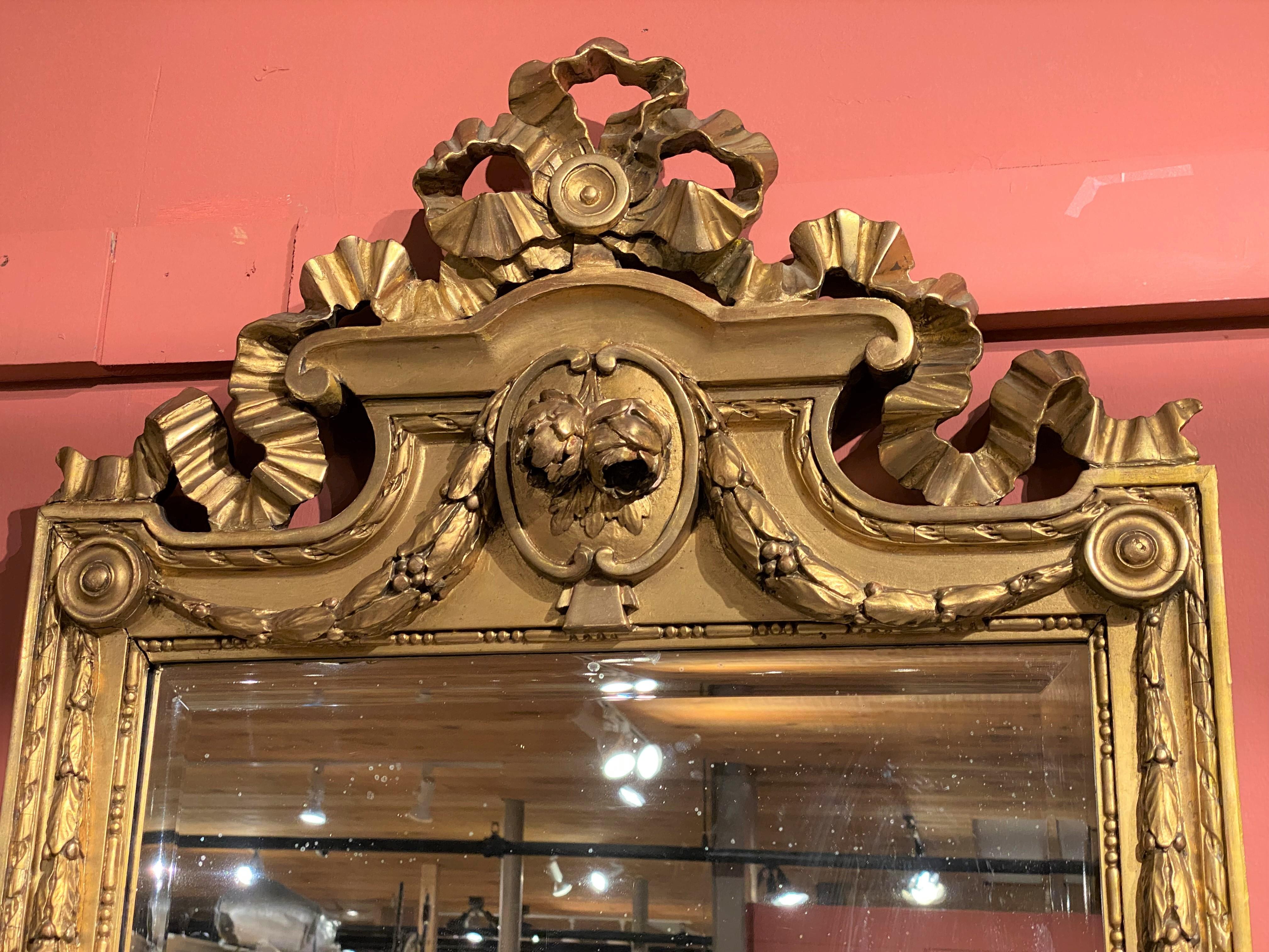 A Swedish Gustavian Period gilt pier mirror with pierce carved ribbon and foliate crest decoration, accented with foliate swags, continued on the beveled mirror surround and base. Dates to the late 18th or early 19th century, in very good condition,