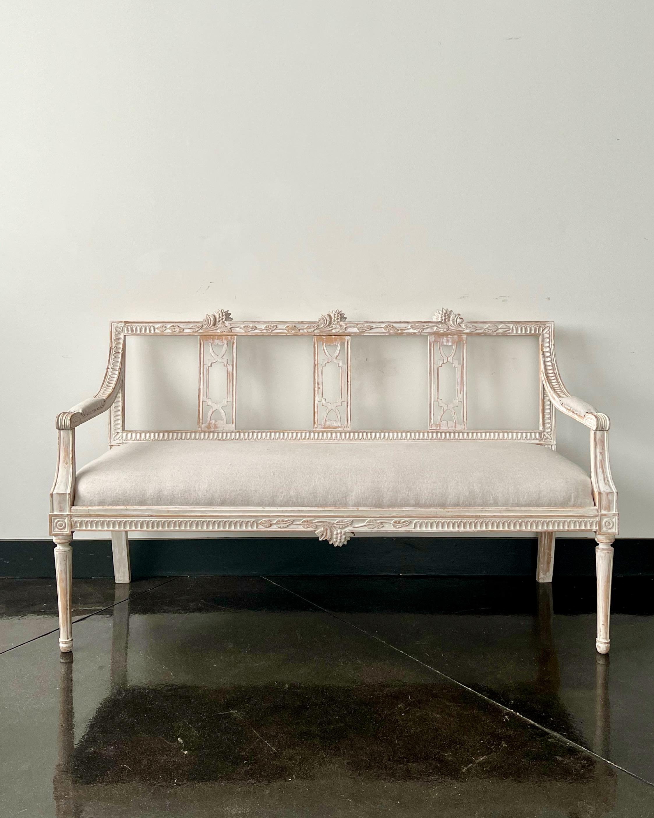 Painted Gustavian period sofa, having the signature fruit and flower carving of the hops plant used by Lindome furniture makers. Hand scraped to the most original color and seat upholstered in pales of pale grey linen. Measures: Seat height