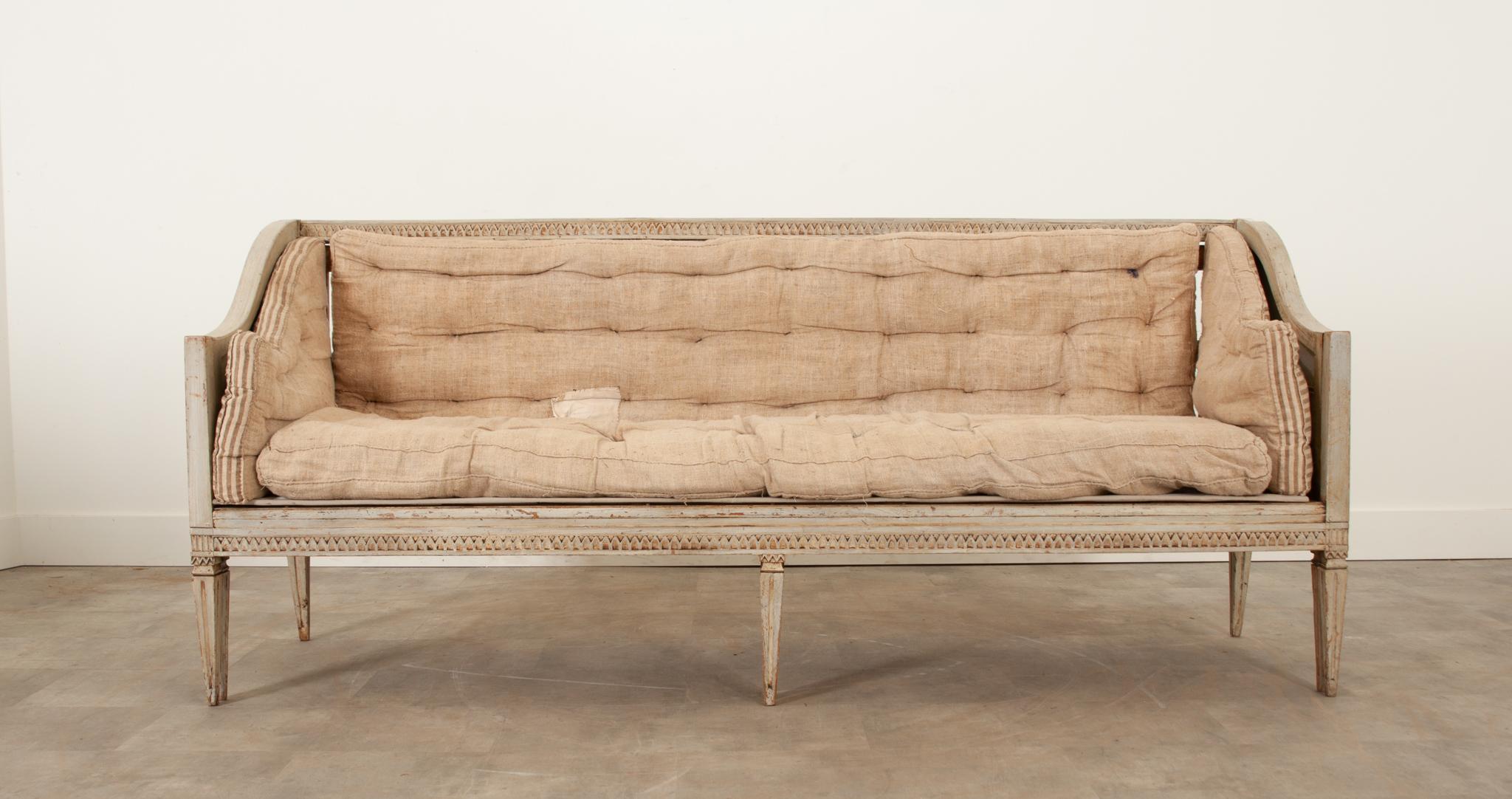 This handsome Swedish Gustavian settee or daybed is an amazing way to add more seating to any space. Its worn finish has a fantastic patina and is aged in all the right spots. Designed with function and simplicity in mind, the hand carved lambs