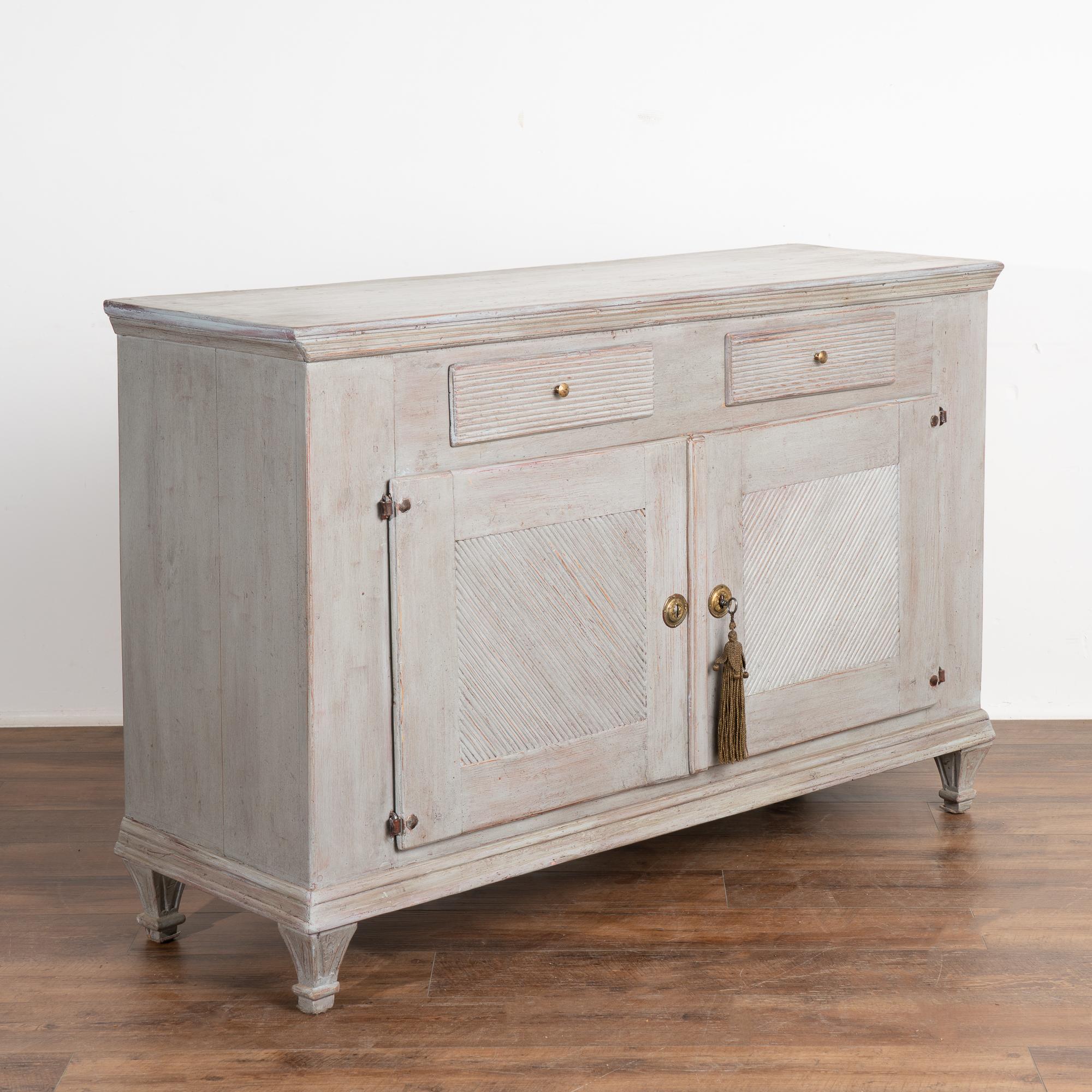 Swedish Gustavian gray painted pine sideboard with two drawers over two cabinet doors resting on tapered fluted feet.
The newer professionally applied soft gray painted finish beautifully compliments the age and grace of this buffet.
Original