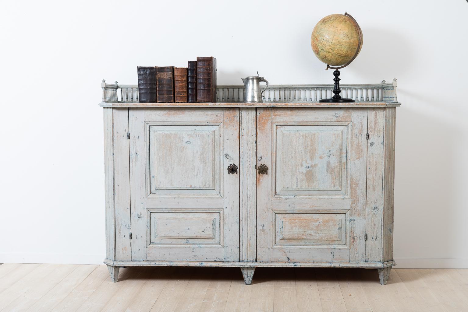Swedish Gustavian sideboard scraped to the original blue / grey paint. The sideboard is decorated with an ornate balustrade. The lock and key are original and in fully functional condition. The interior has two drawers and two shelfs. The sideboard