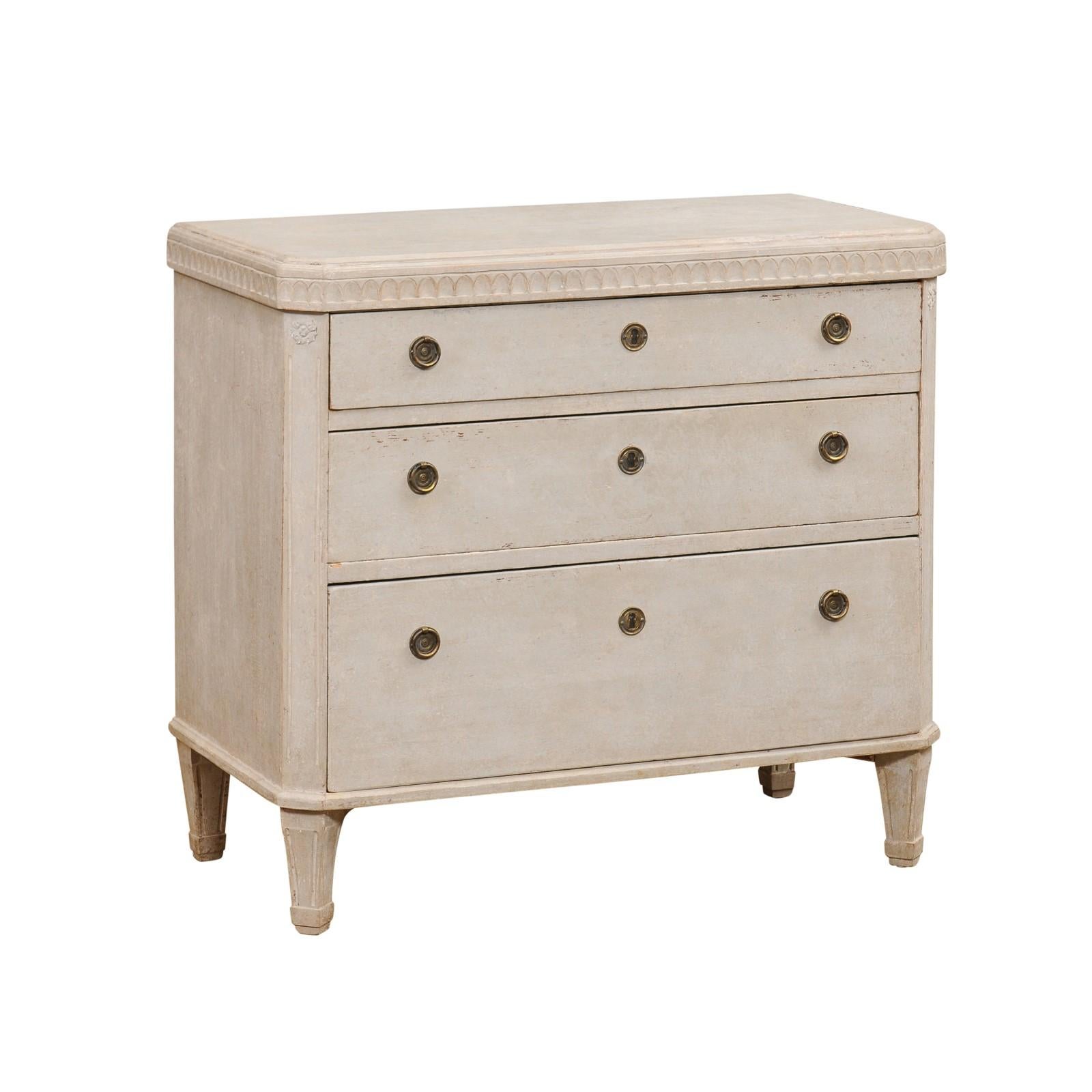 A Swedish Gustavian Style painted wood chest from the mid 19th Century, with carved frieze, three graduated drawers and short tapered feet. Created in Sweden during the second quarter of the 19th Century, this painted chest features a rectangular