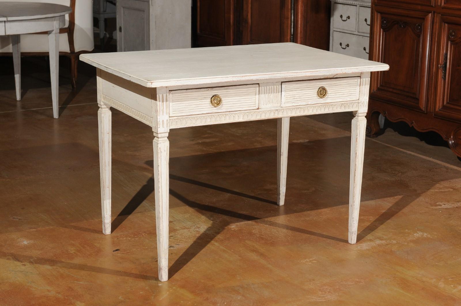 A Swedish Gustavian style painted desk from the mid-19th century, with two drawers, fluted motifs and tapered legs. Created in Sweden during the 1850s, this Gustavian style painted desk features a rectangular top sitting above two drawers adorned