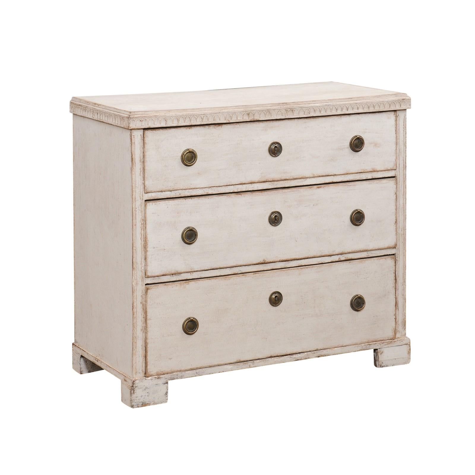 A Swedish Gustavian Style painted wood chest from the Mid-19th Century, with three graduated drawers, carved motifs, block feet and Classical brass hardware. Created in Sweden during the 1850s, this painted chest showcases the stylistic