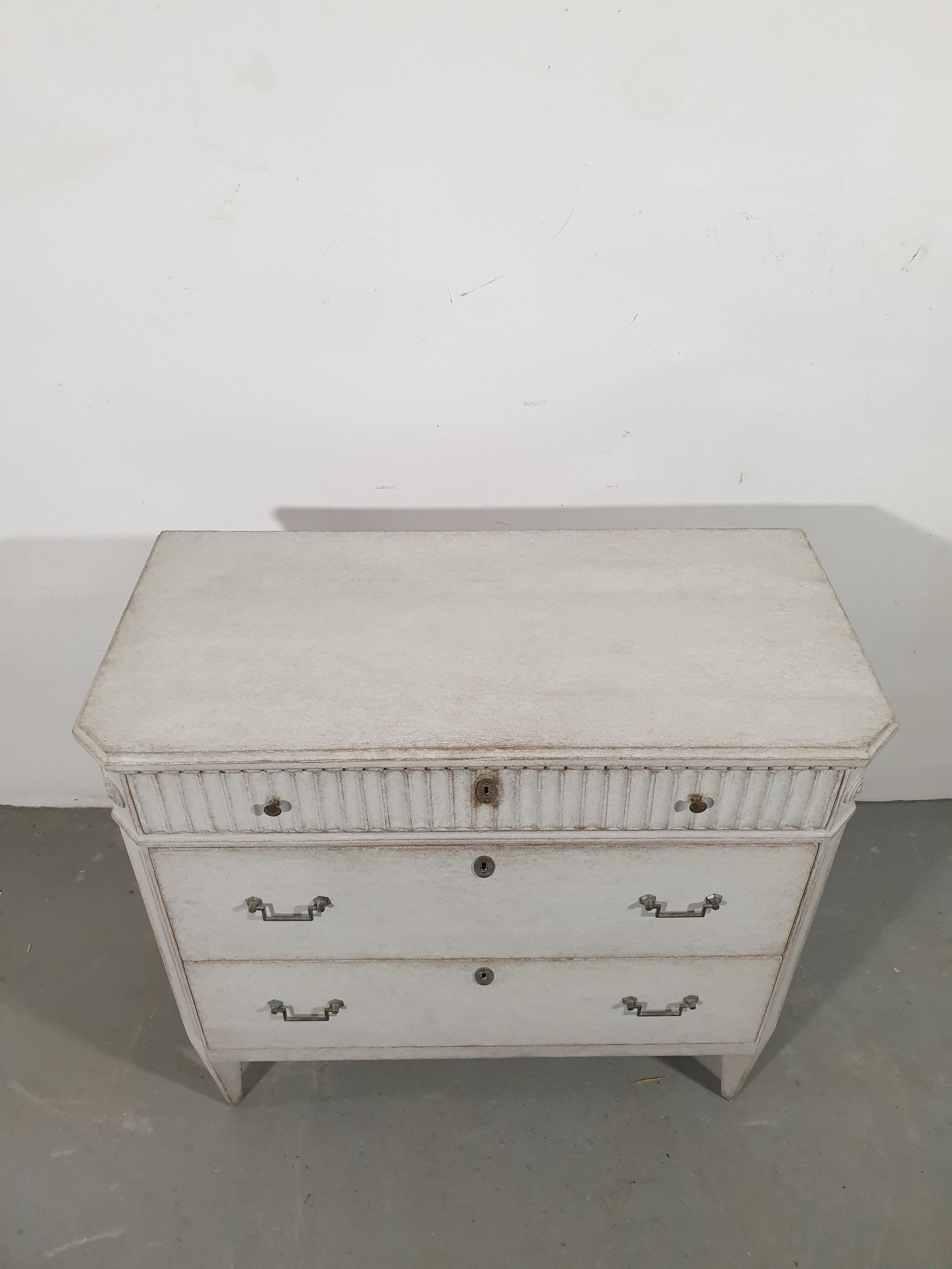 A Swedish Gustavian style chest from circa 1860 with three drawers, light gray painted finish, reeded accents, dentil molding and tapered legs. Embrace the understated elegance of Swedish Gustavian design with this exquisite chest from circa 1860.