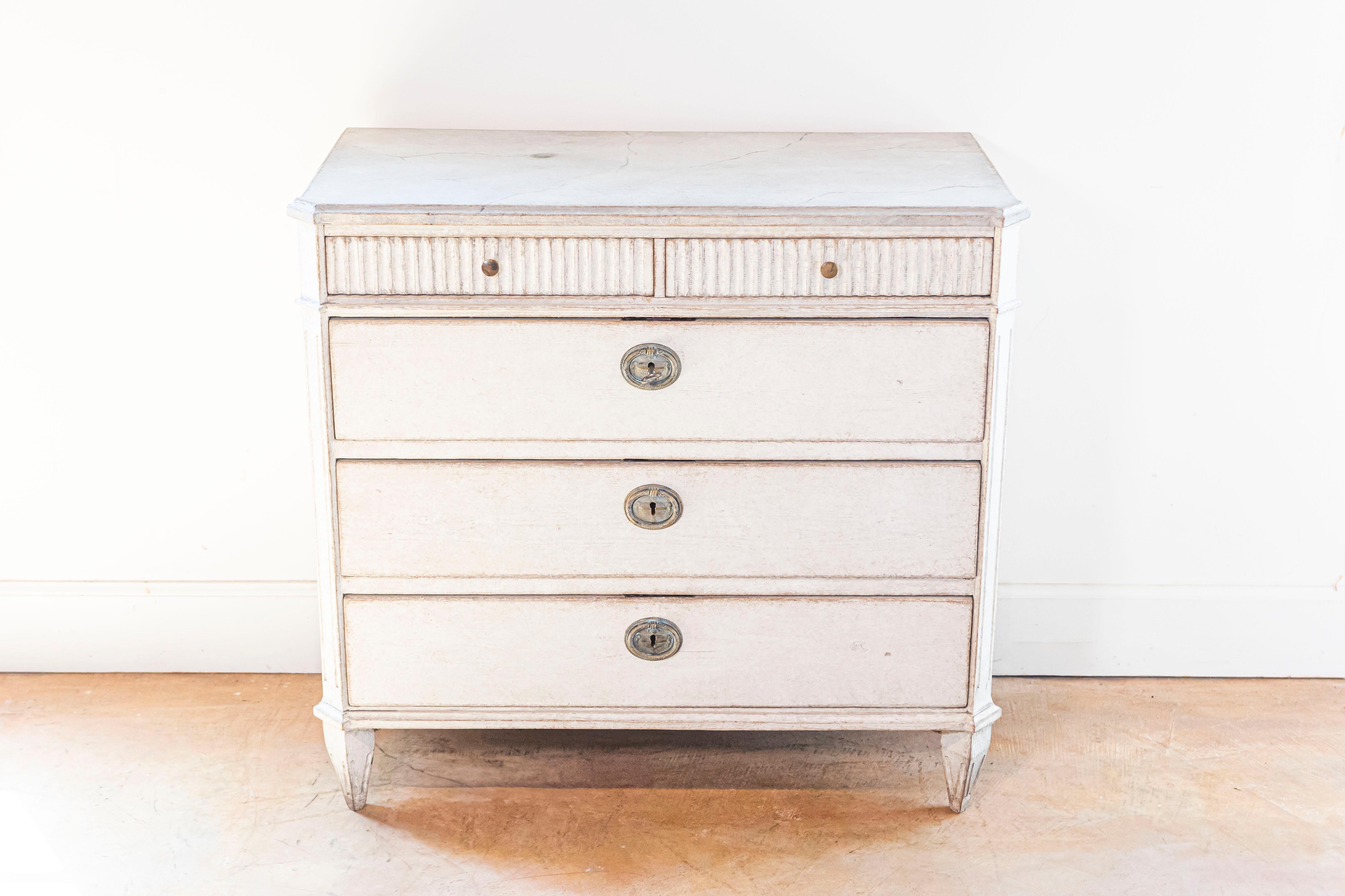 Cassettone svedese dipinto in stile gustaviano del 1860 circa con cinque cassetti, piano discretamente marmorizzato, scanalature intagliate, piedi affusolati e montanti laterali scanalati. Prova la tranquilla eleganza del design scandinavo con