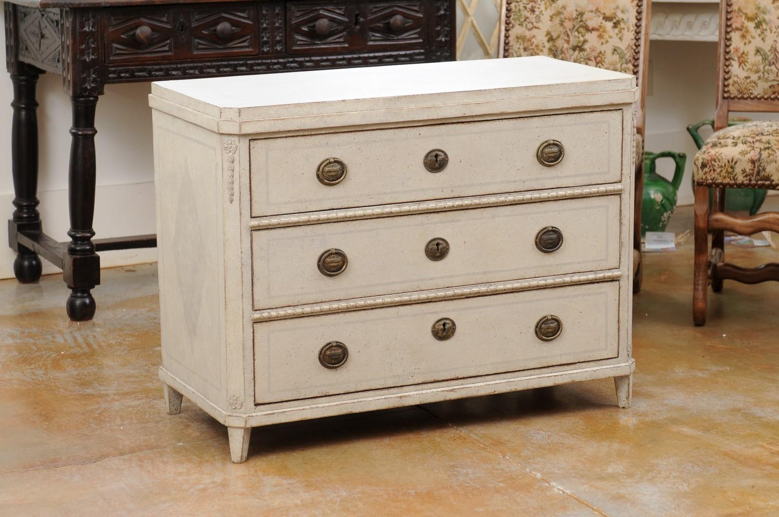 A Swedish Gustavian style painted wood chest from the mid 19th century, with three drawers, raised top and carved motifs. Created in Sweden during the third quarter of the 19th century, this painted chest features a rectangular raised top with