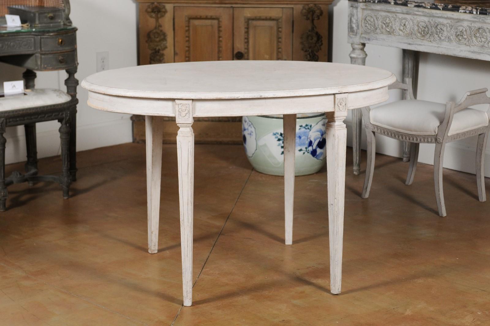 A Swedish Gustavian style painted table from the late 19th century, with oval top and tapered legs. Born in Sweden during the last quarter of the 19th century, this painted Gustavian table features an oval top with beveled edges, sitting above four