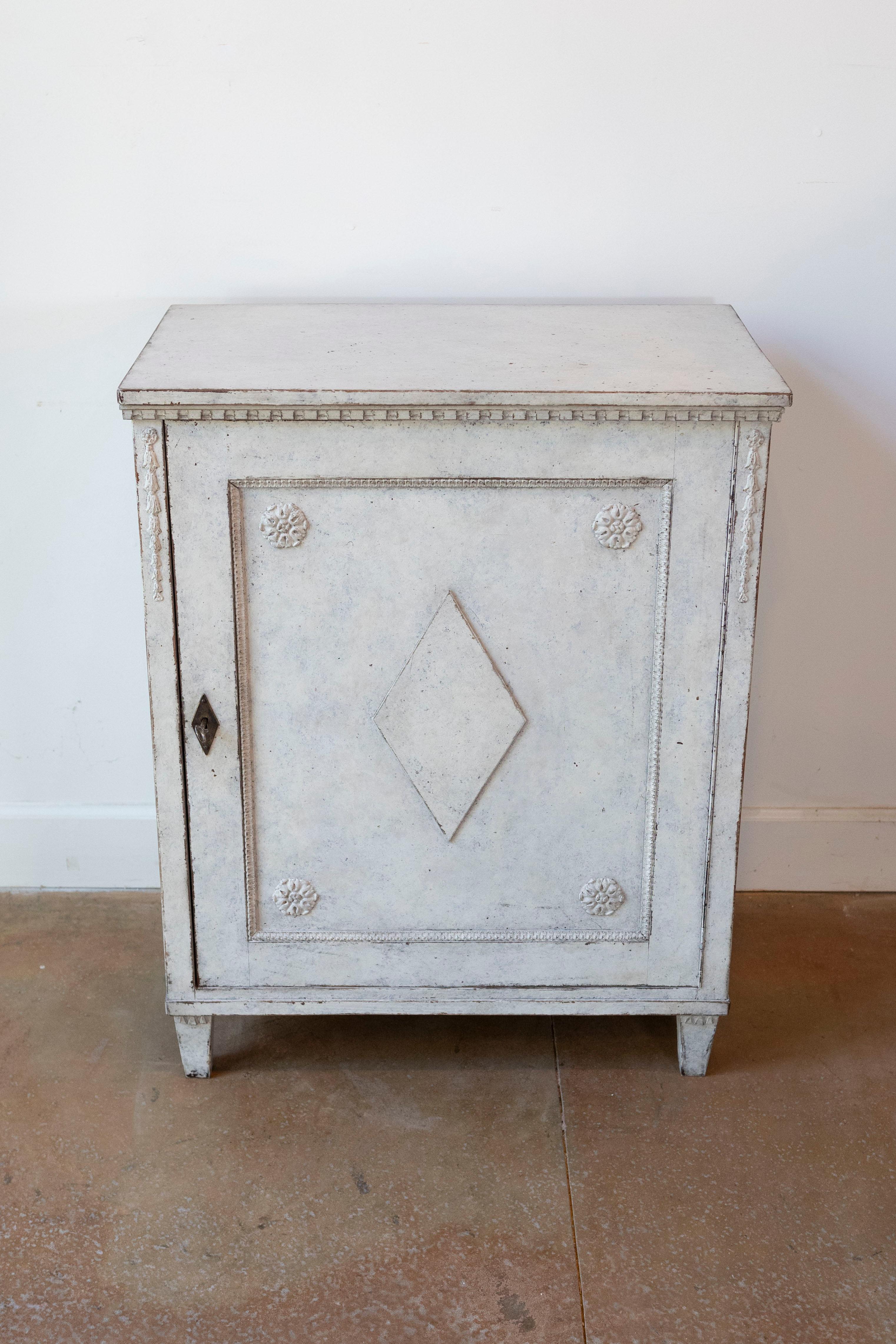 Armario de madera pintada de estilo sueco Gustaviano de finales del siglo XIX, con una sola puerta, rosetas talladas, motivos romboidales y molduras dentiladas. Creado en Suecia durante el último cuarto del siglo XIX, este armario pintado presenta