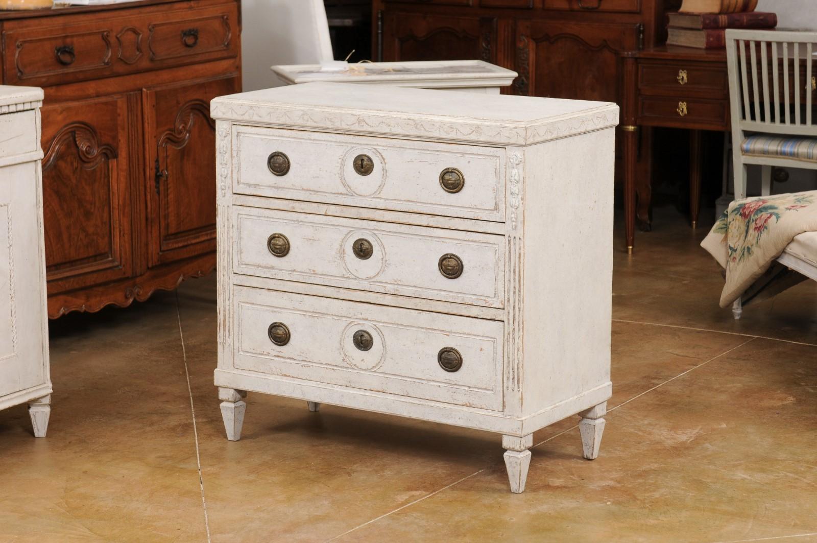 A Swedish Gustavian style painted wood chest of drawers from the late 19th century, with swag frieze, carved side posts and tapered feet. Created in Sweden during the last quarter of the 19th century, this painted chest showcases the stylistic