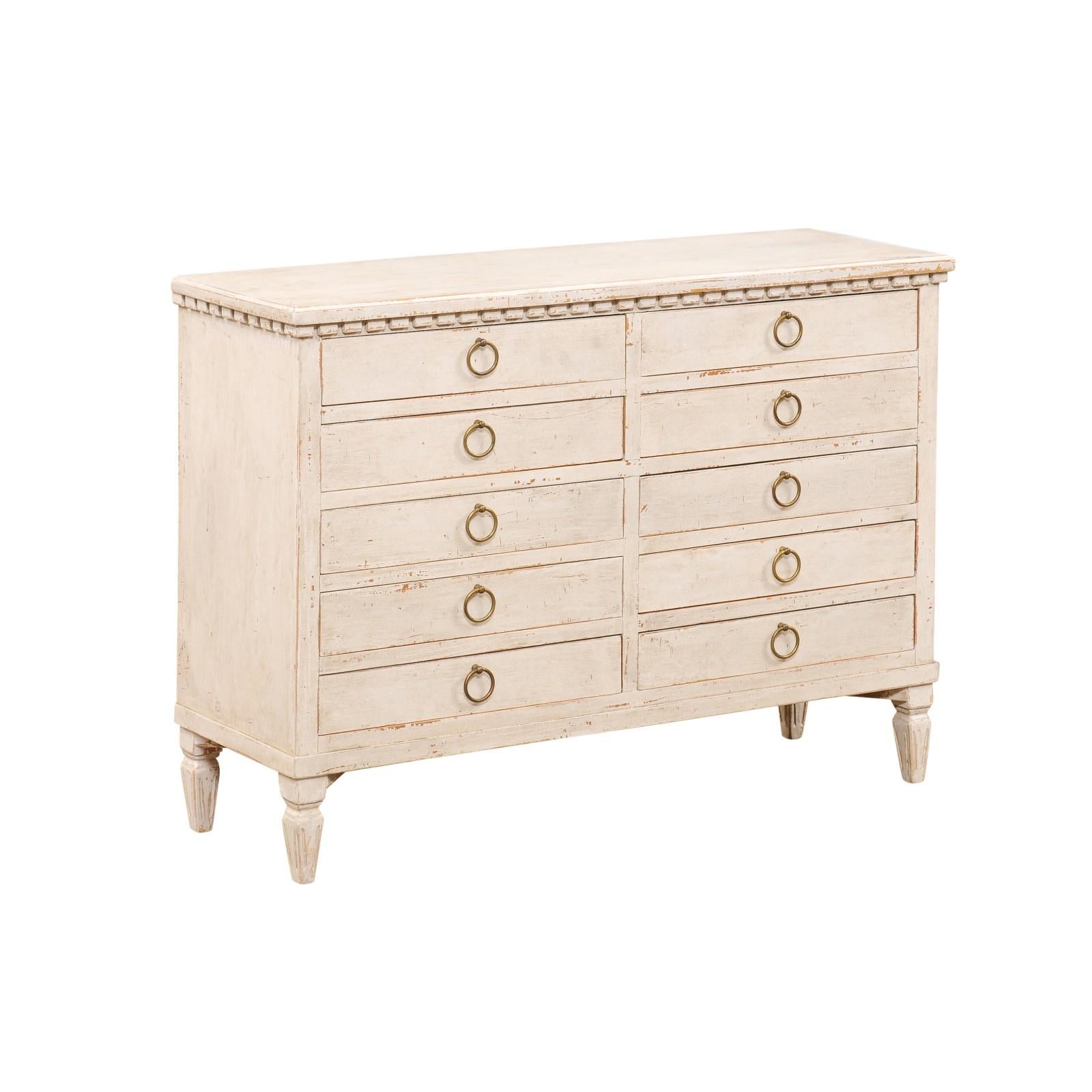 A Swedish Gustavian style painted wood apothecary chest from the late 19th century, with carved dentil molding, 10 drawers, brass ring pull hardware and tapered feet. Created in Sweden during the last decade of the 19th century, this painted chest