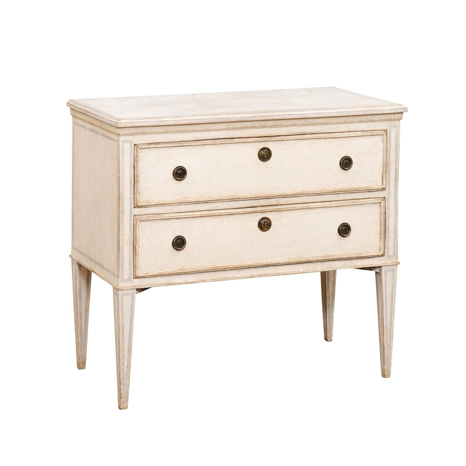 A Swedish Gustavian style painted chest circa 1890 with two drawers, carved fluted molding, light grey painted outlines and tapered legs. Embrace the enduring charm of Nordic design with this Swedish Gustavian style painted chest, circa 1890. This
