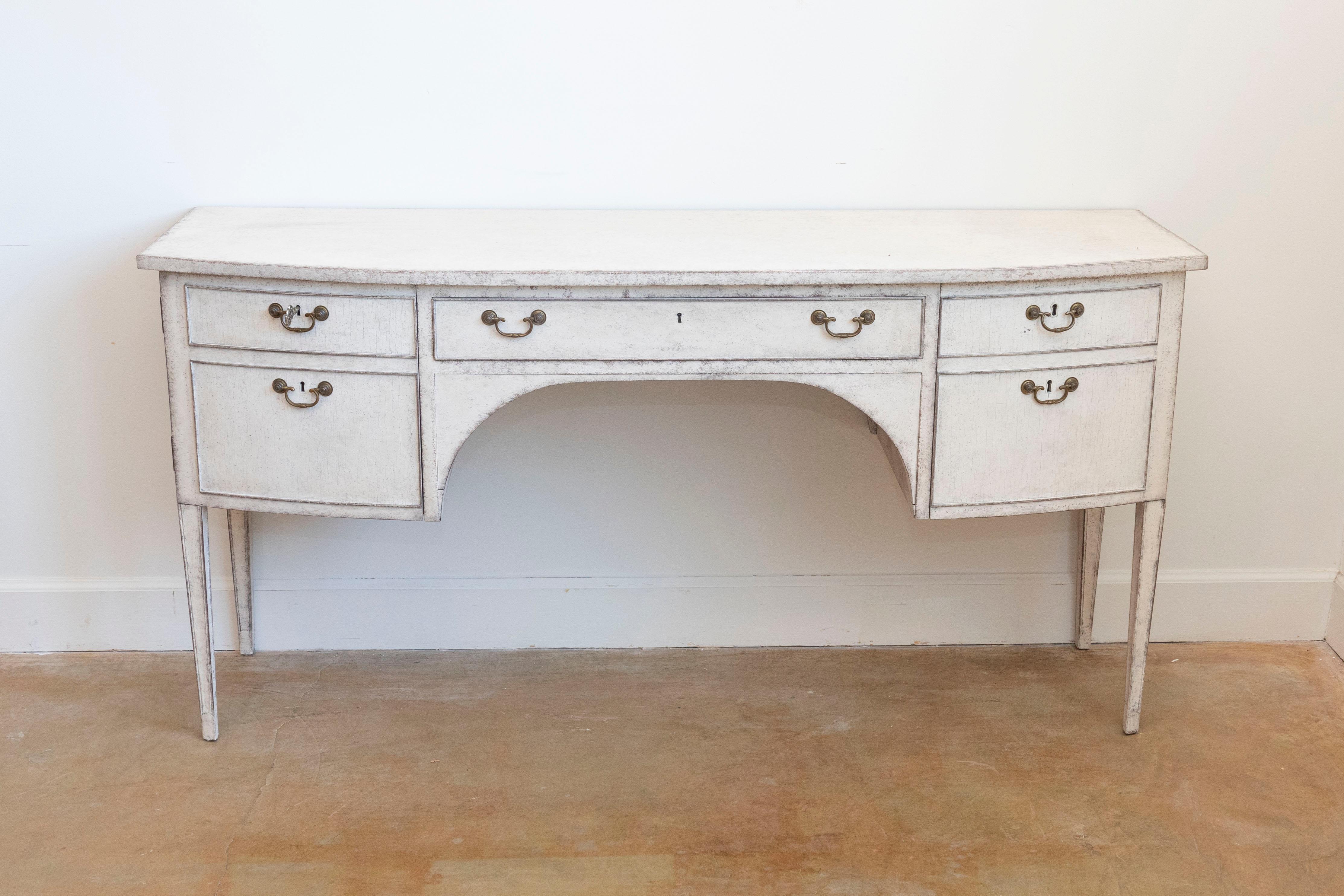 A Swedish Gustavian style bow front painted wood sideboard or desk from the early 20th century, with single drawer, two doors and tapered legs. Created in Sweden during the Turn of the Century which saw the transition between the 19th to the 20th,
