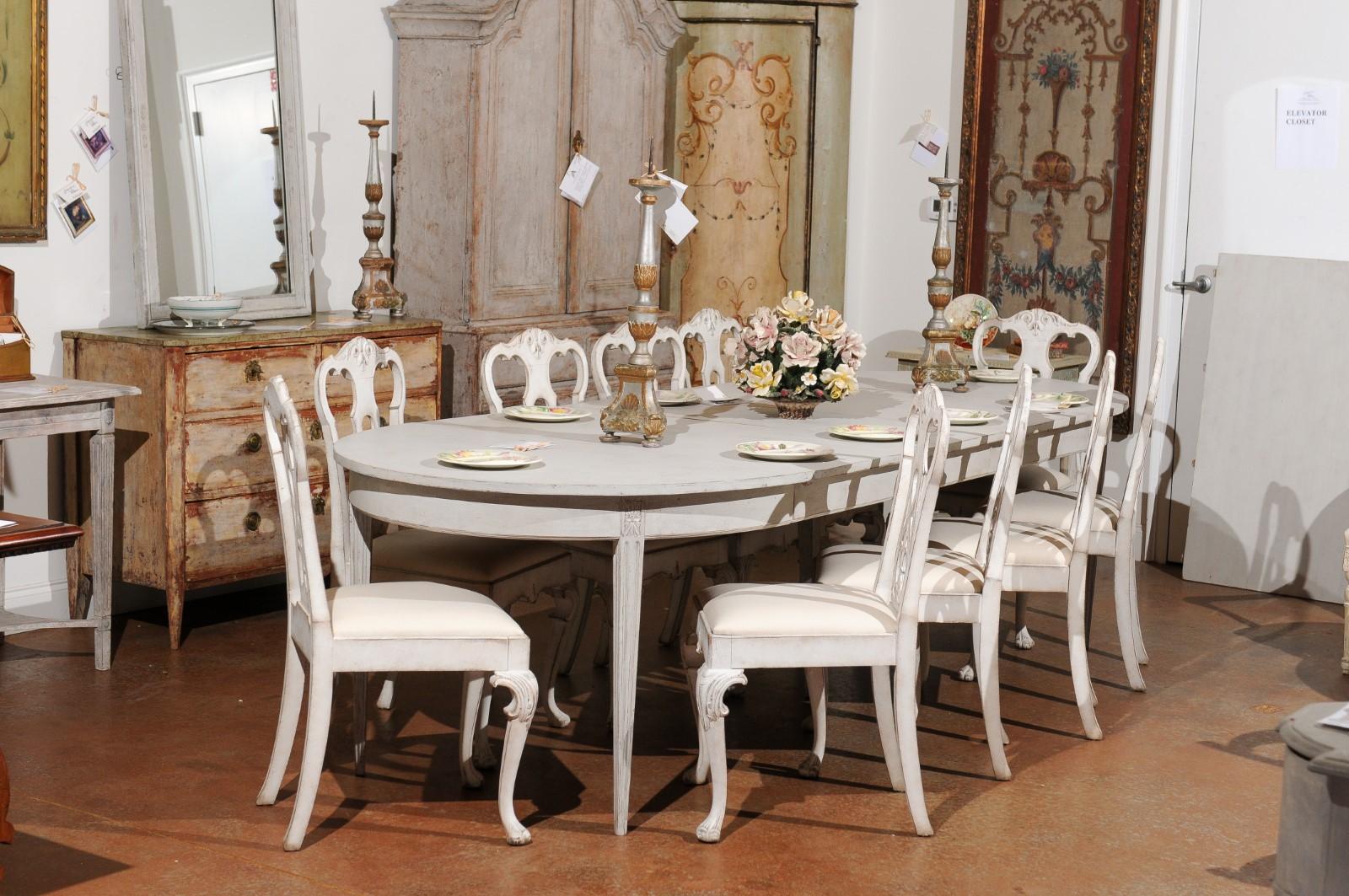 A Swedish Gustavian style painted wood extension dining room table from the 19th century, with four new leaves. Created in Sweden during the 19th century, this Swedish dining room table features an oval top resting on an apron simple adorned with