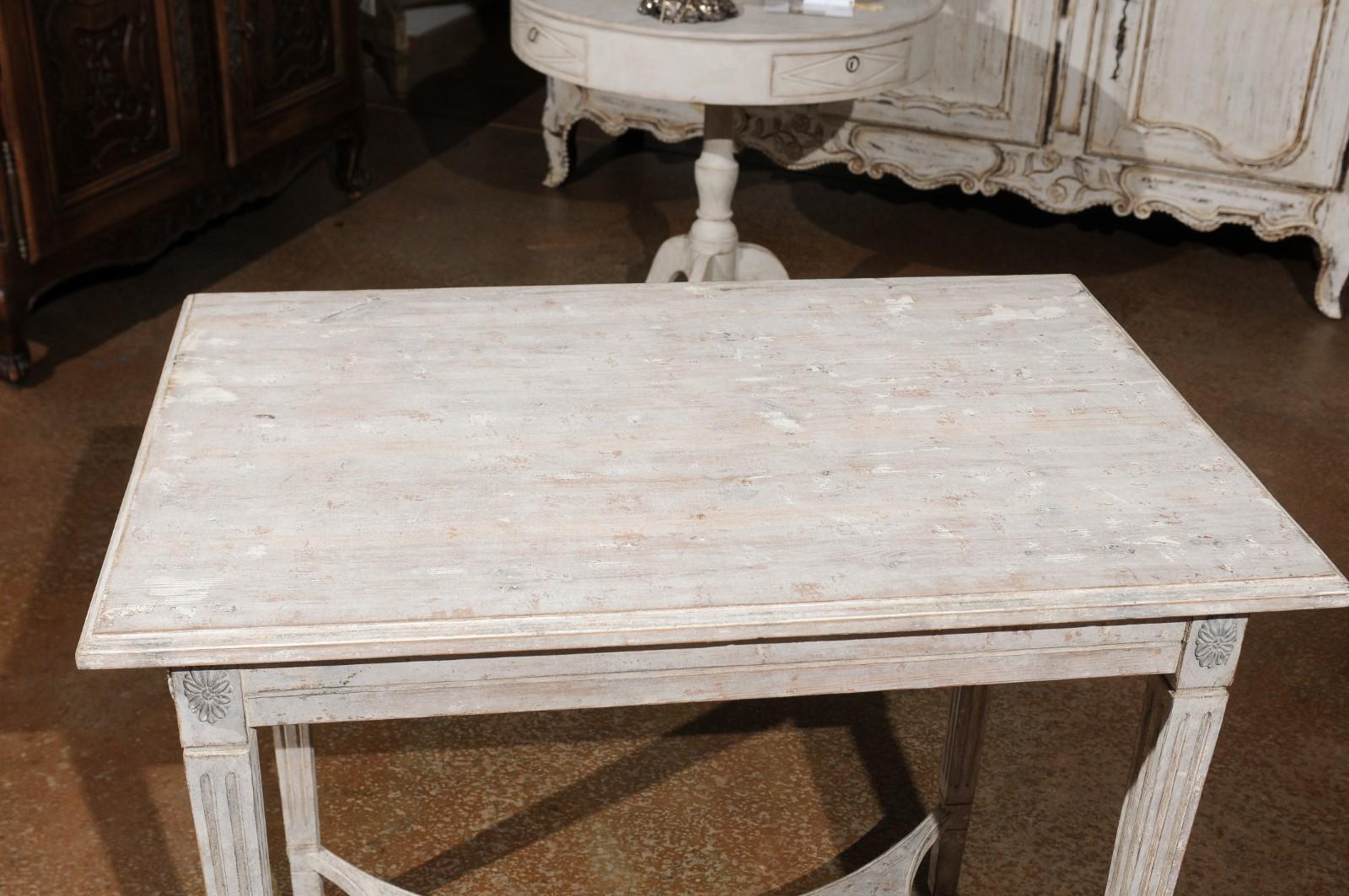 Table console suédoise de style gustavien en bois peint du 19e siècle, avec rosettes sculptées et traverse incurvée. Créée en Suède au XIXe siècle, cette table console peinte présente un plateau rectangulaire au-dessus d'un tablier simple accentué